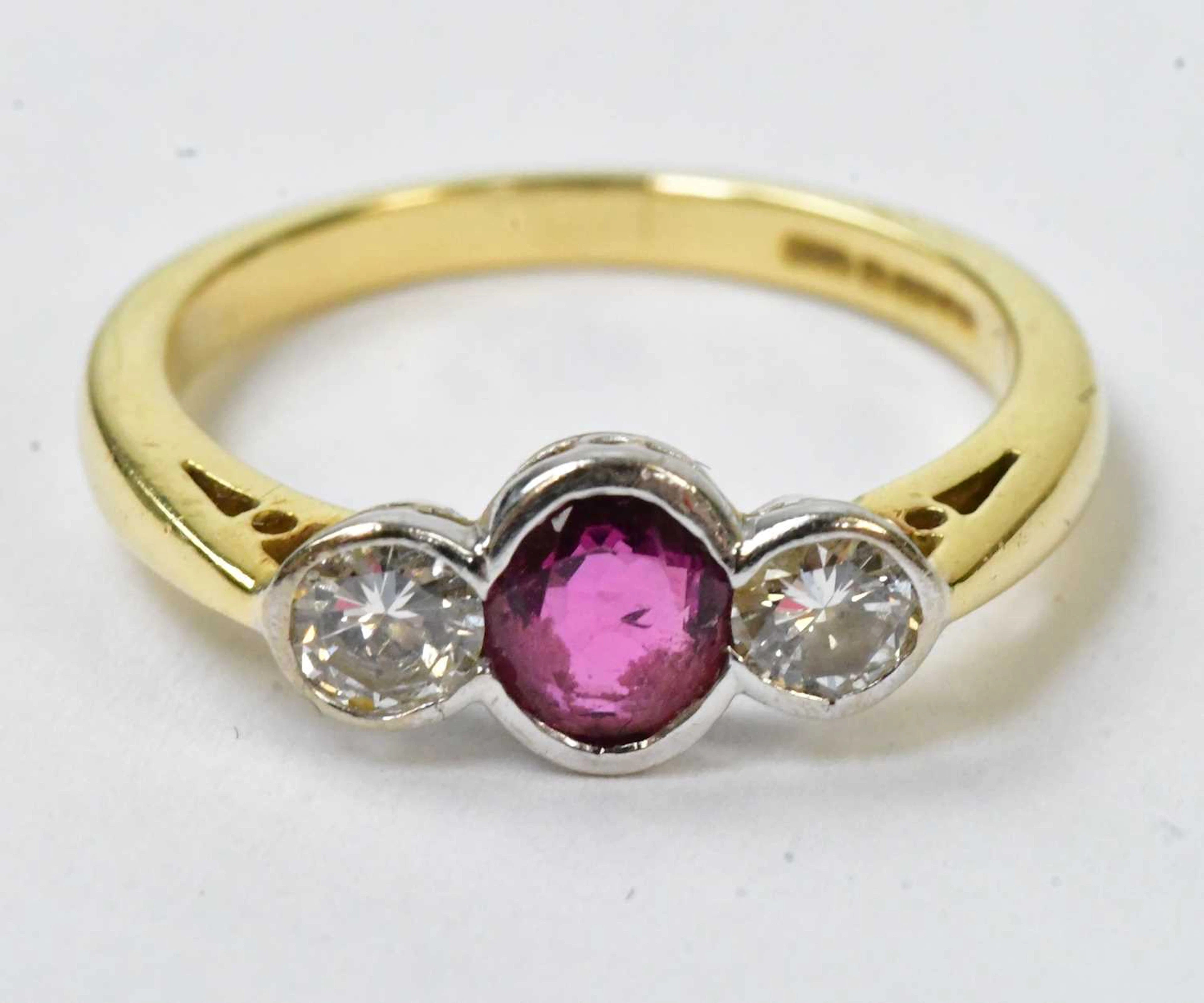 An 18ct yellow gold ring set with a central ruby flanked...