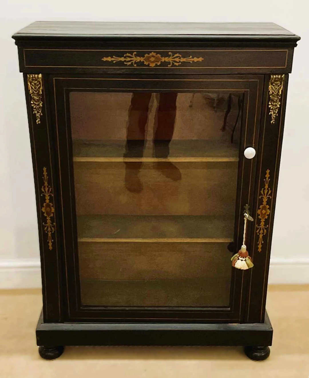 An ebonised pier cabinet with a single glazed door