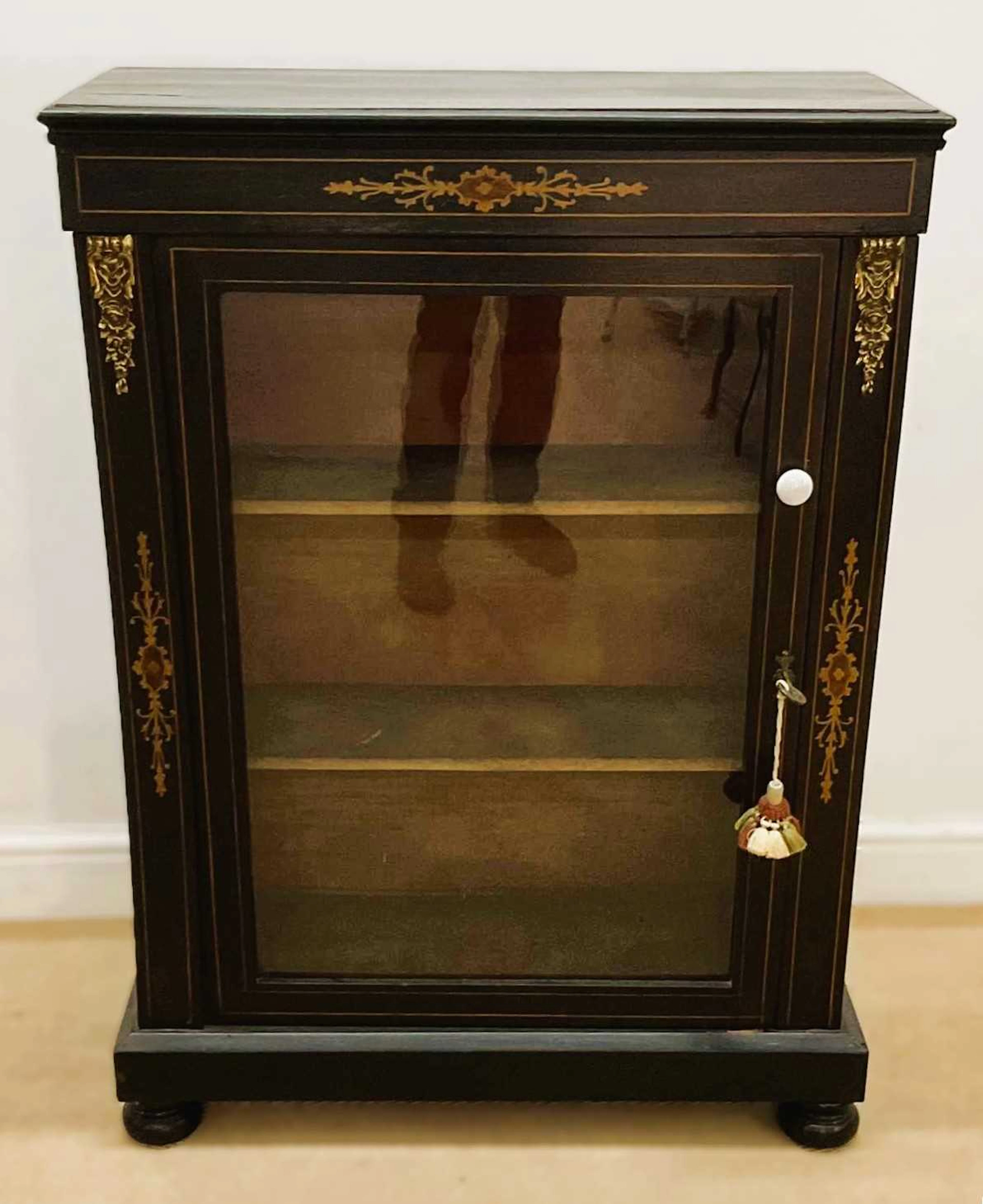 An ebonised pier cabinet with a single glazed door