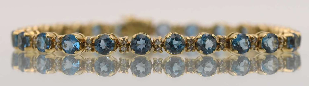 A 9ct yellow gold line bracelet set with twenty-seven claw set blue stones