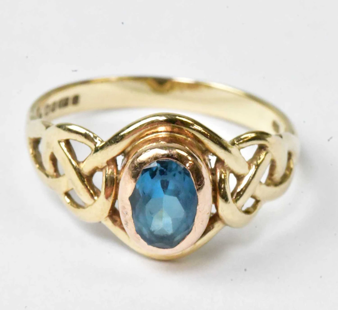 A 9ct yellow gold ring set with a central oval blue stone