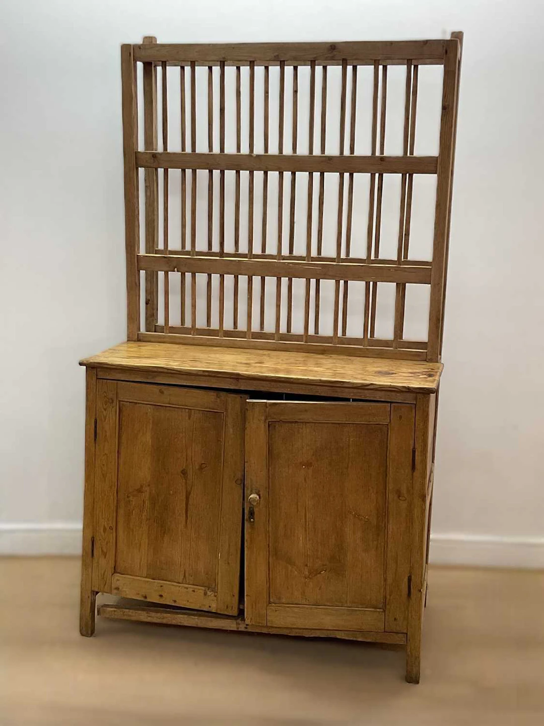 A pine kitchen dresser with spindle back plate rack and cupboard beneath