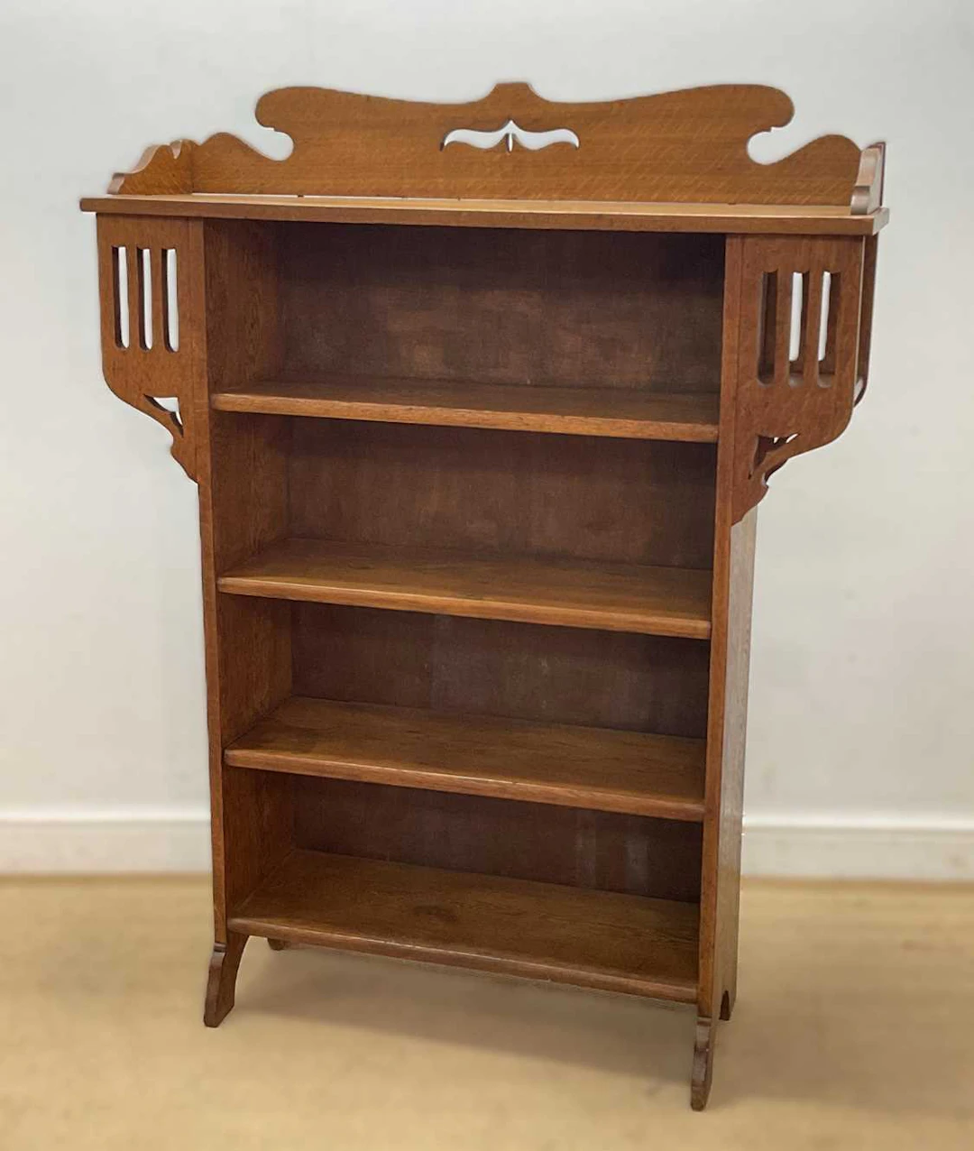 An Arts and Crafts oak open bookcase with pierced sides and backboard