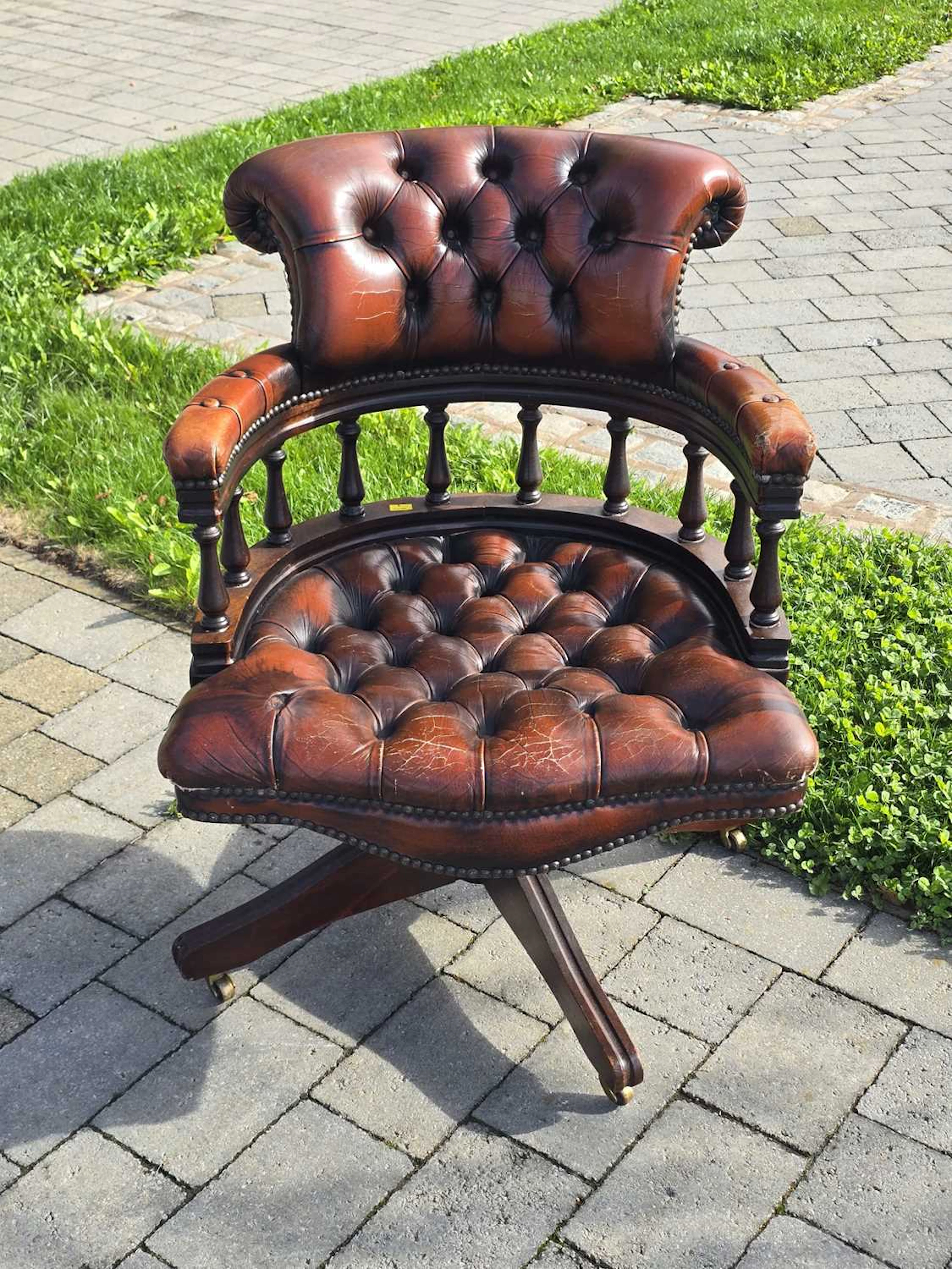 A reproduction brown leather button-back swivel desk chair