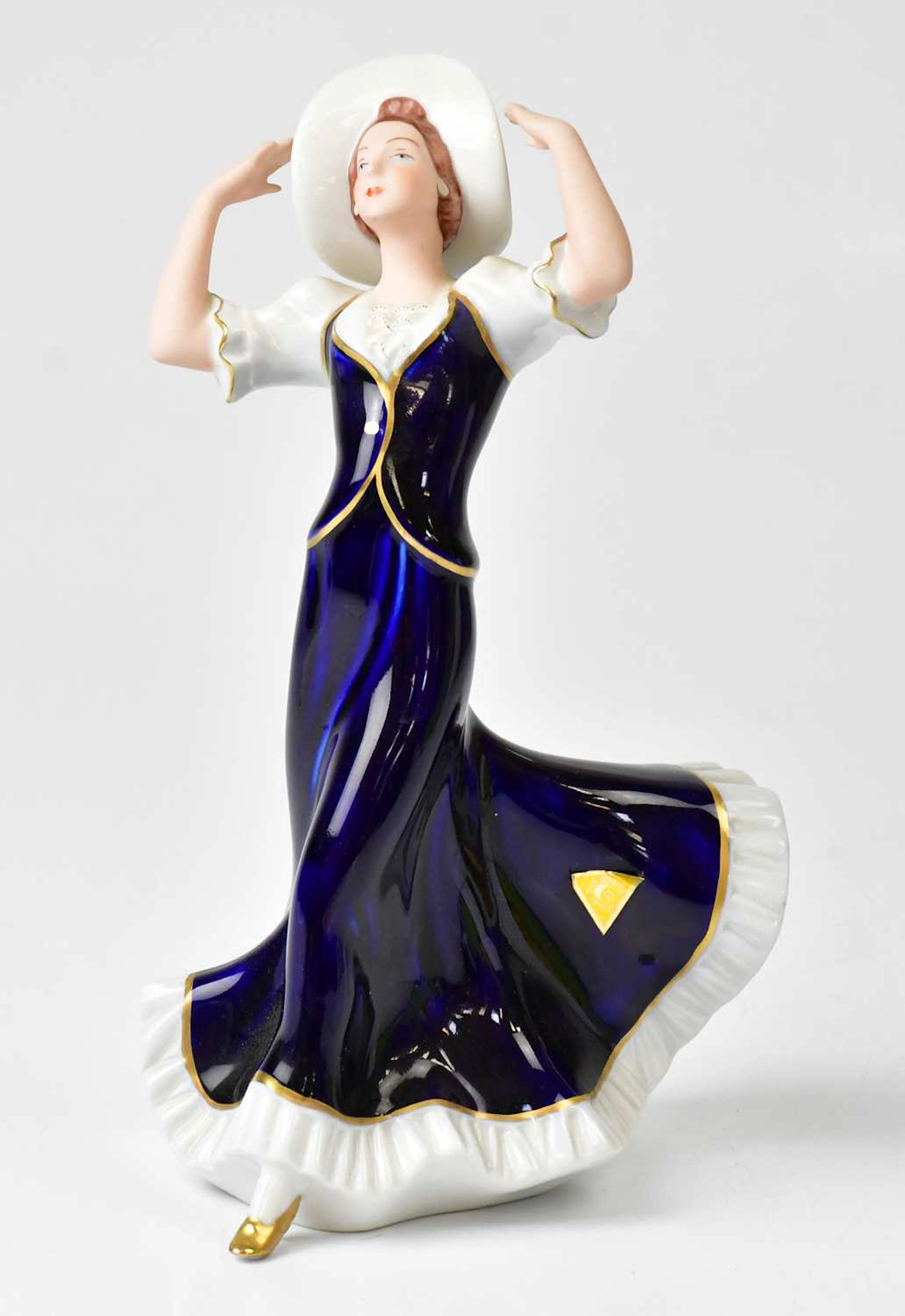 ROYAL DUX; a porcelain figure of a lady holding onto her hat