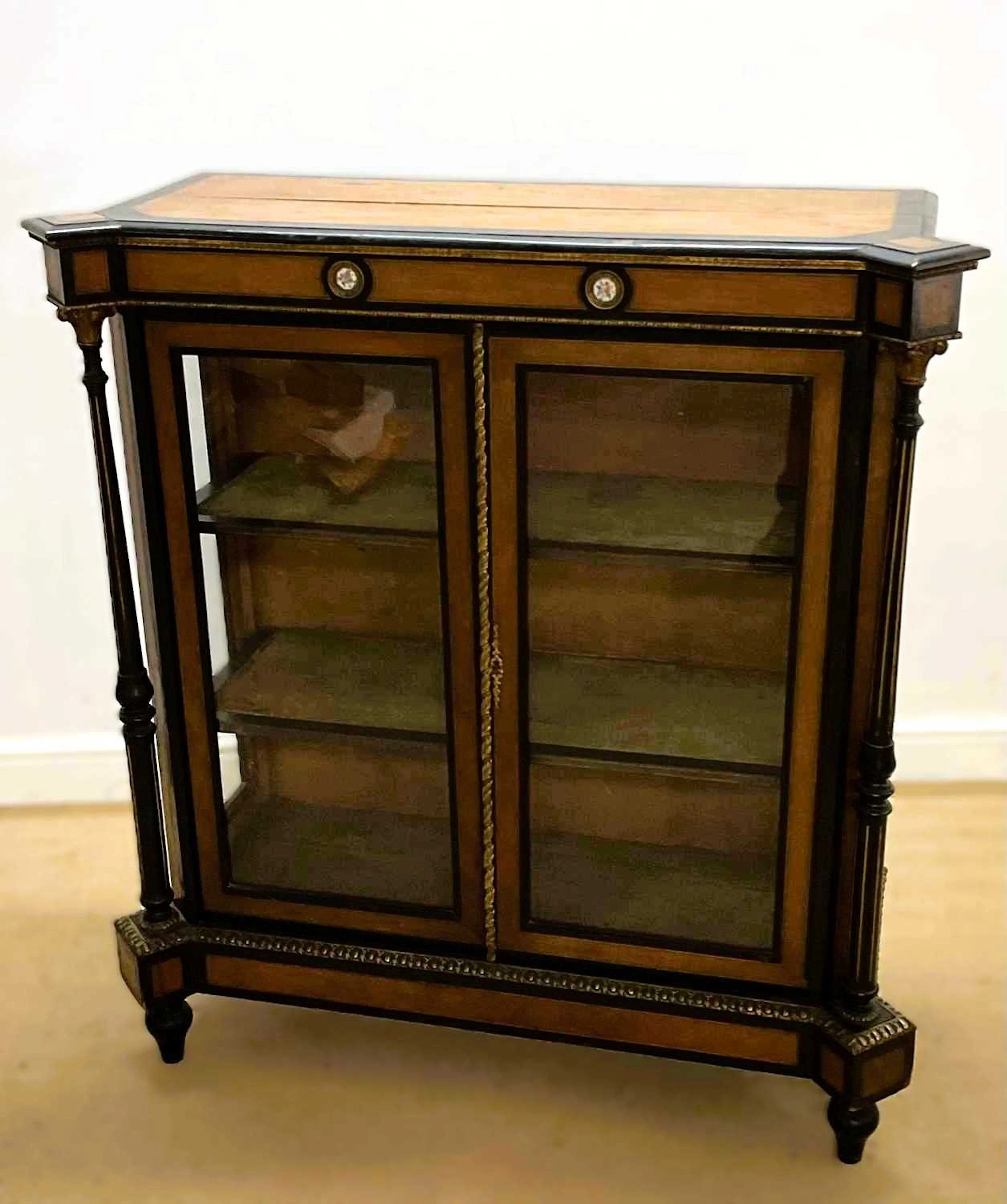 A satinwood pier cabinet with twin glazed doors and two fitted shelves
