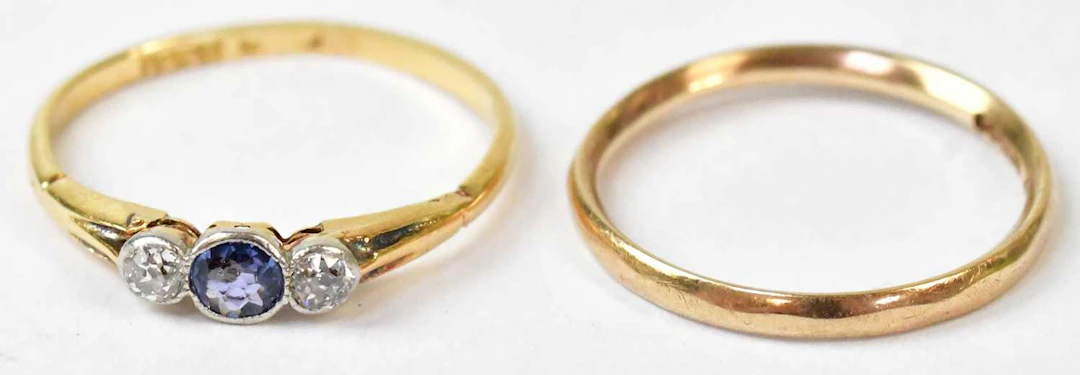 A yellow metal ring set with a central sapphire flanked by two diamonds