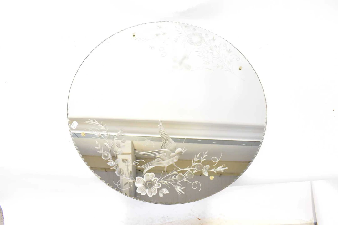 A vintage circular bevelled edge mirror with etched...