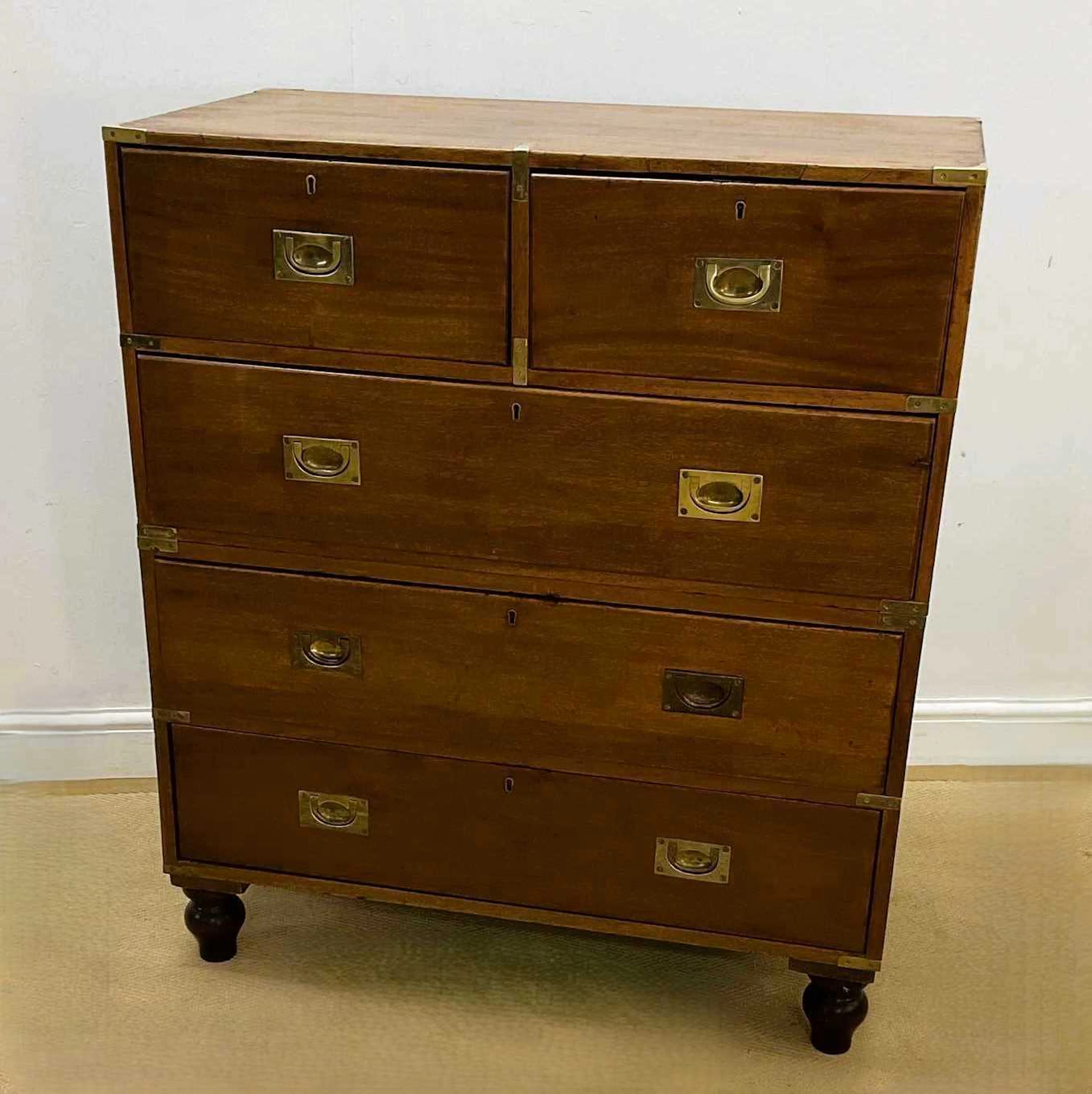 A teak campaign chest of two short over three long drawers