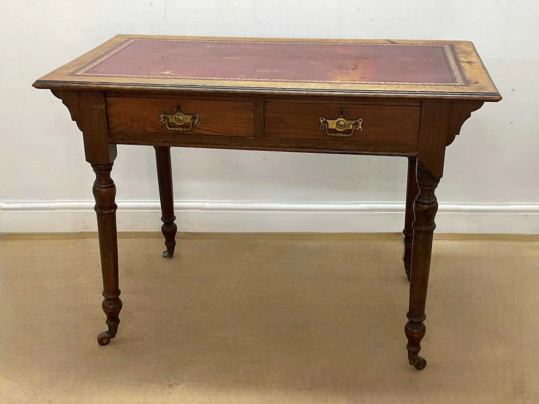 A Victorian oak writing table with red leather inset writing surface