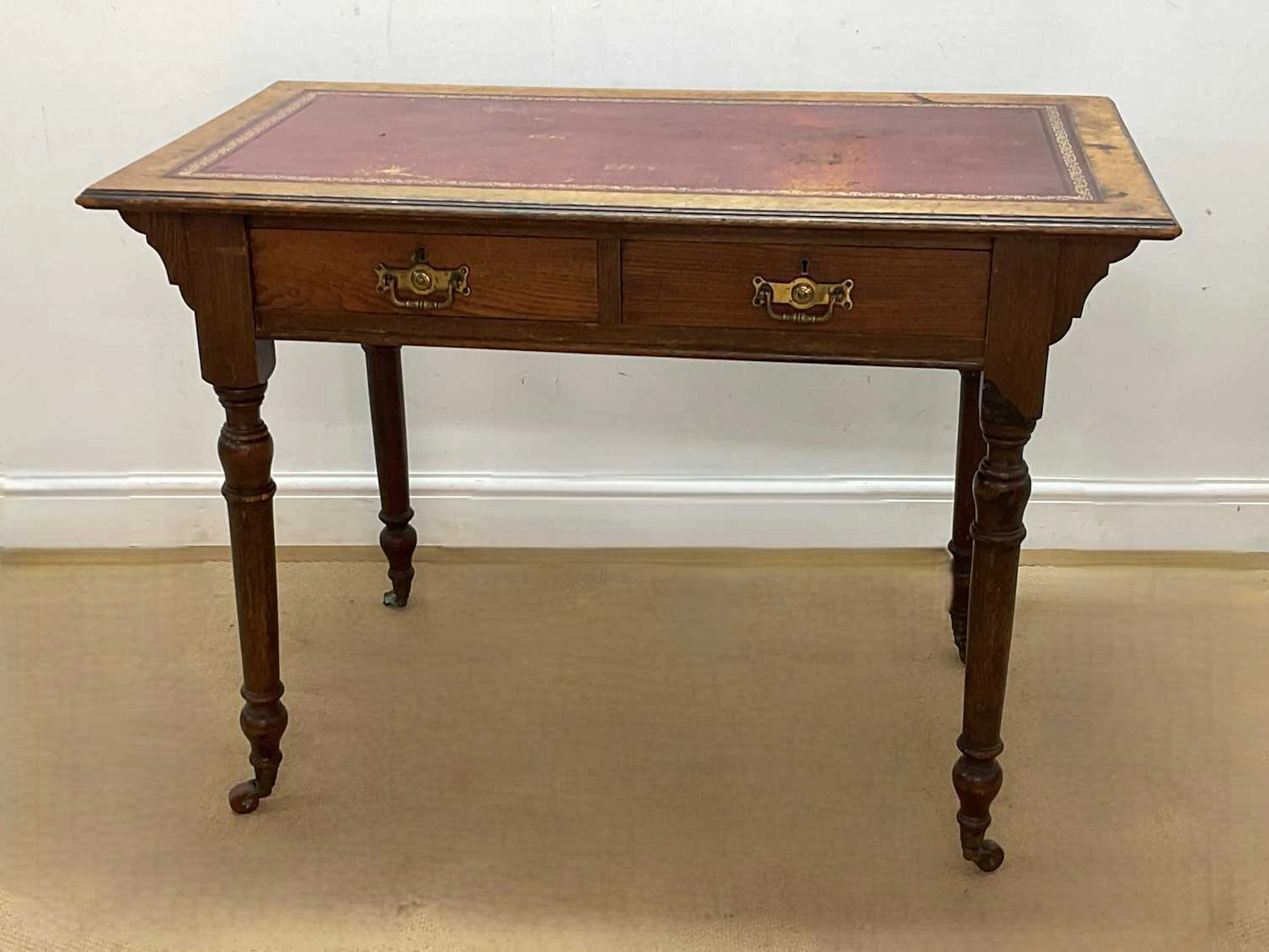 A Victorian oak writing table with red leather inset writing surface