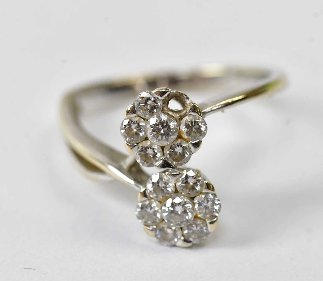 An 18ct white gold ring set with two flower head clusters...