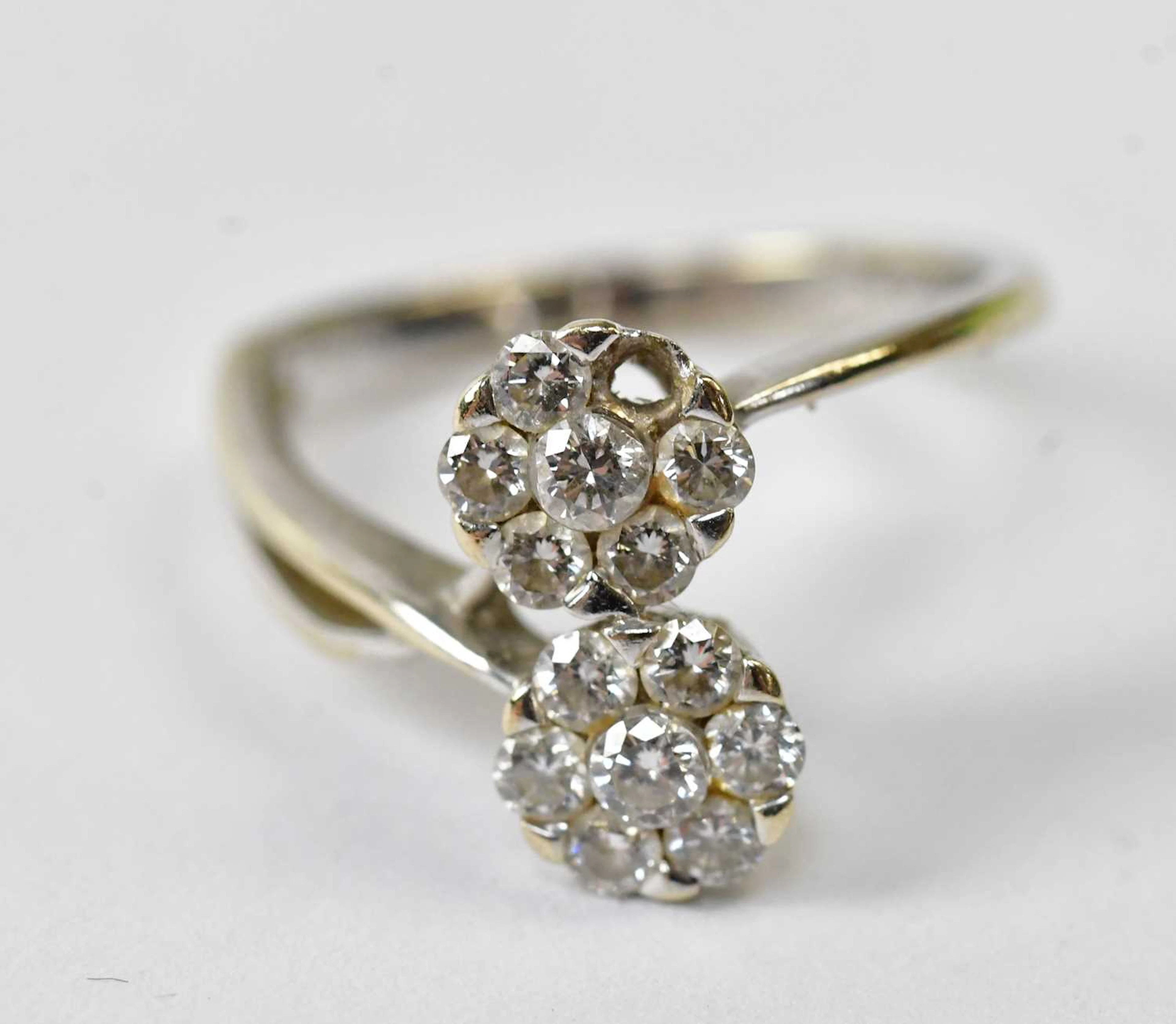 An 18ct white gold ring set with two flower head clusters...
