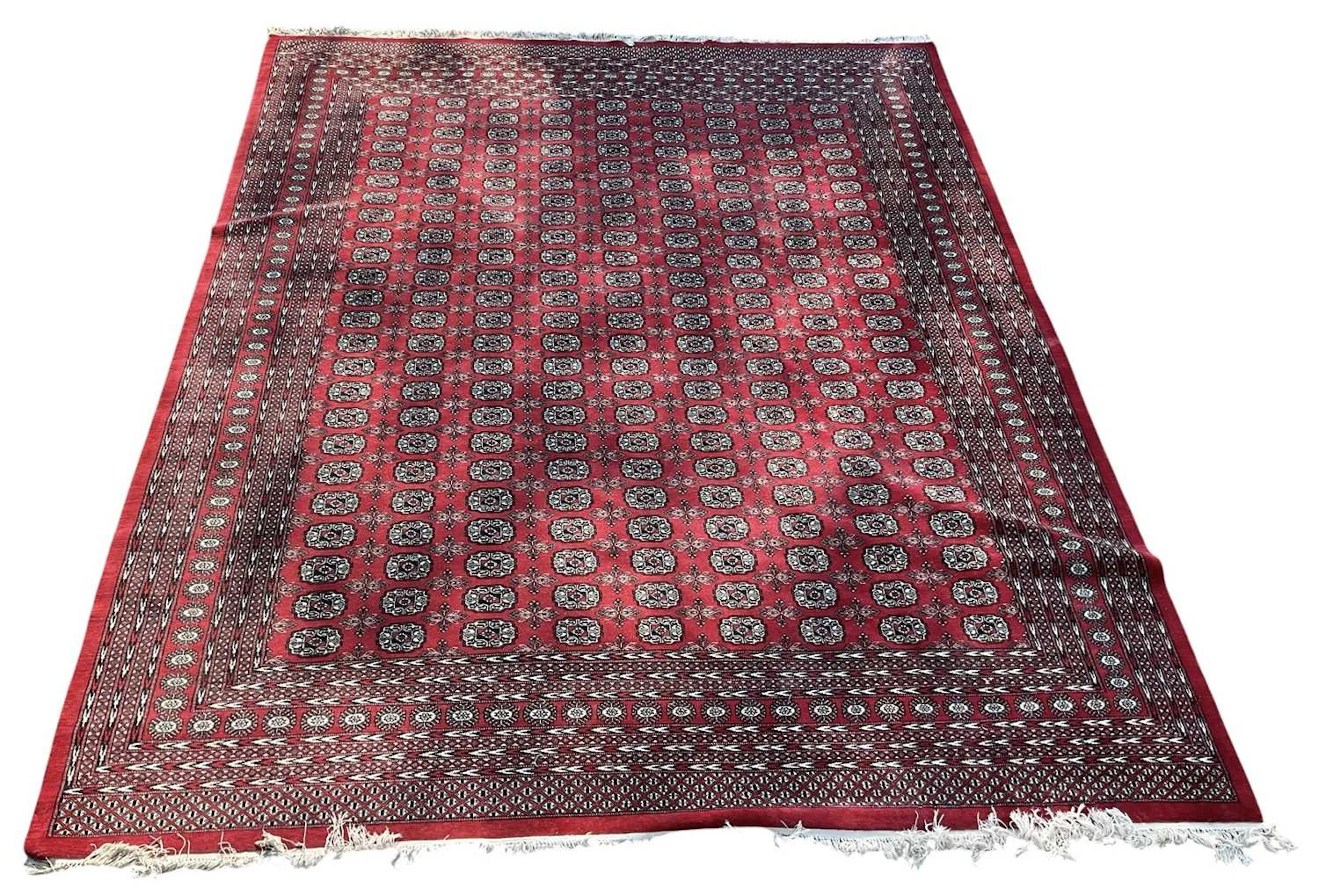 A large modern red ground hand woven Pakistani Bokhara woollen ground carpet