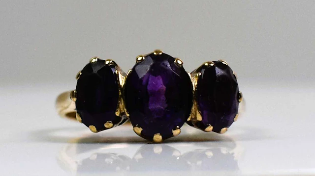 A 9ct yellow gold and three stone amethyst ring