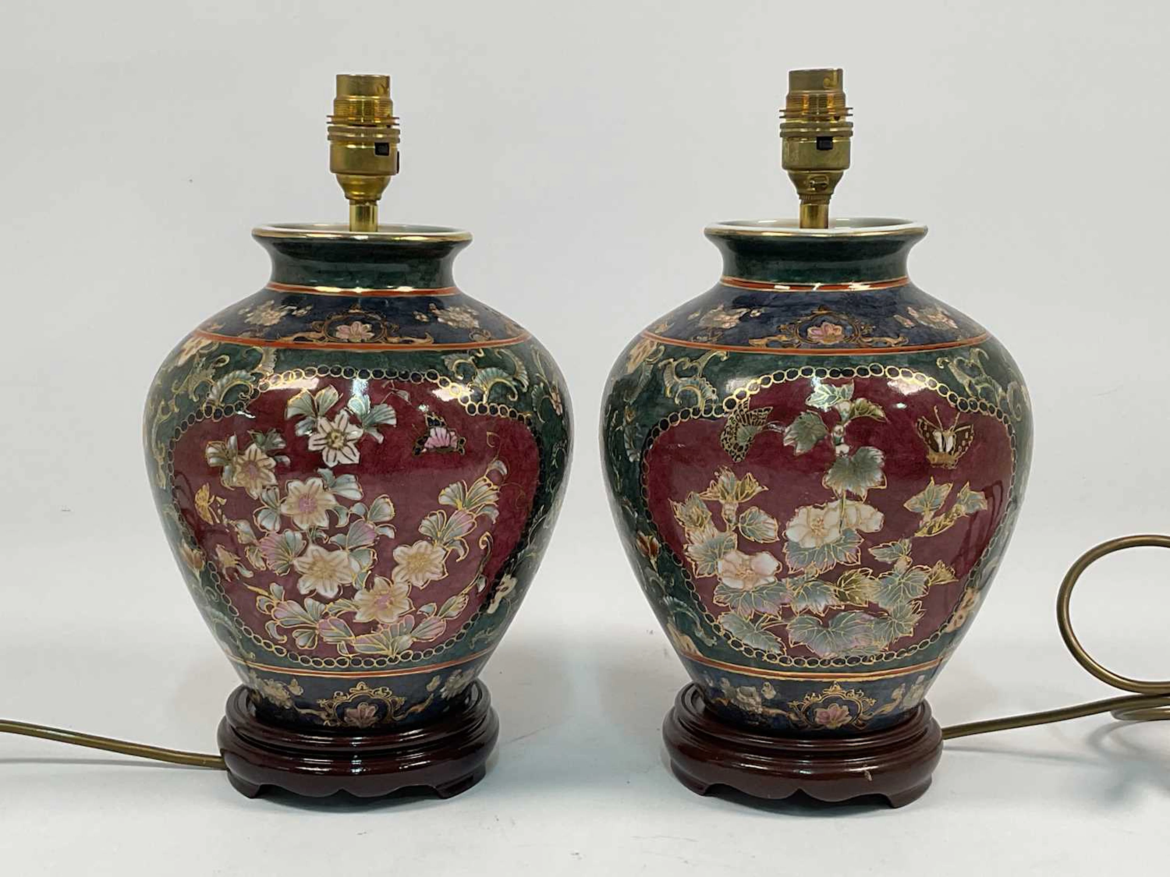 A pair of decorative floral ceramic table lamps on turned wooden bases