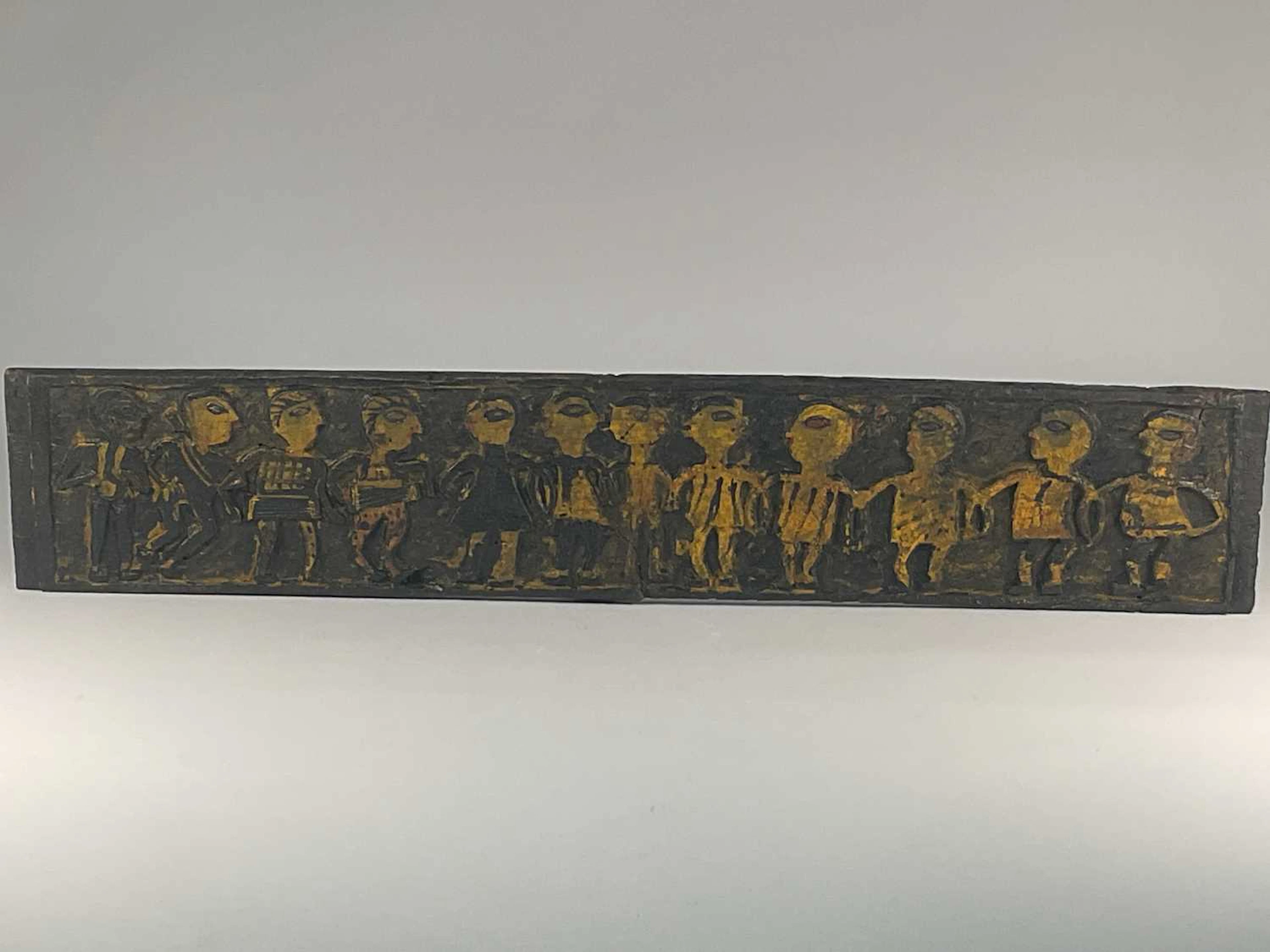 A carved wooden panel depicting figures linking arms
