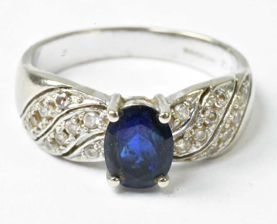A 14ct white gold ring set with a central blue stone and tiny cubic zirconia