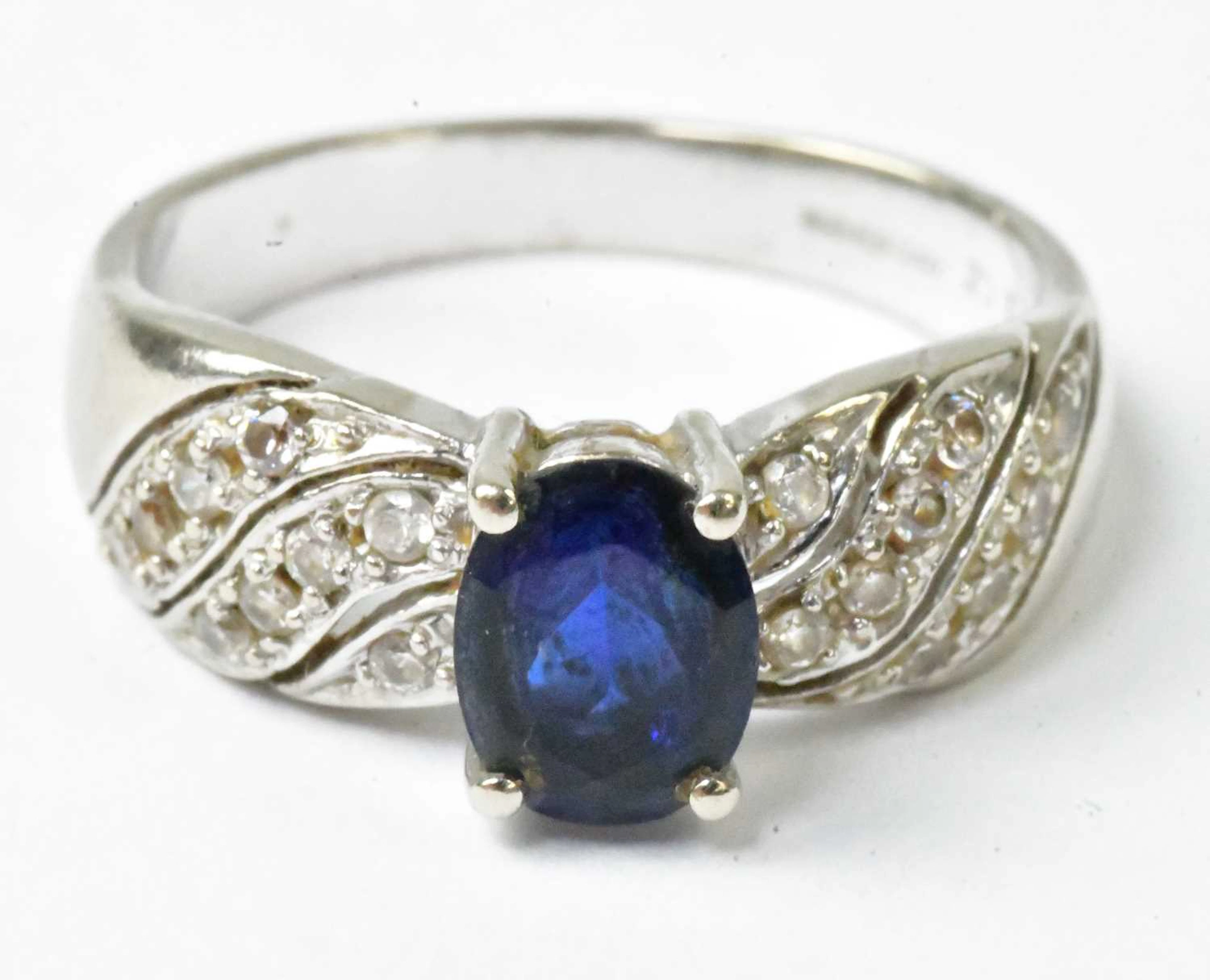 A 14ct white gold ring set with a central blue stone and tiny cubic zirconia