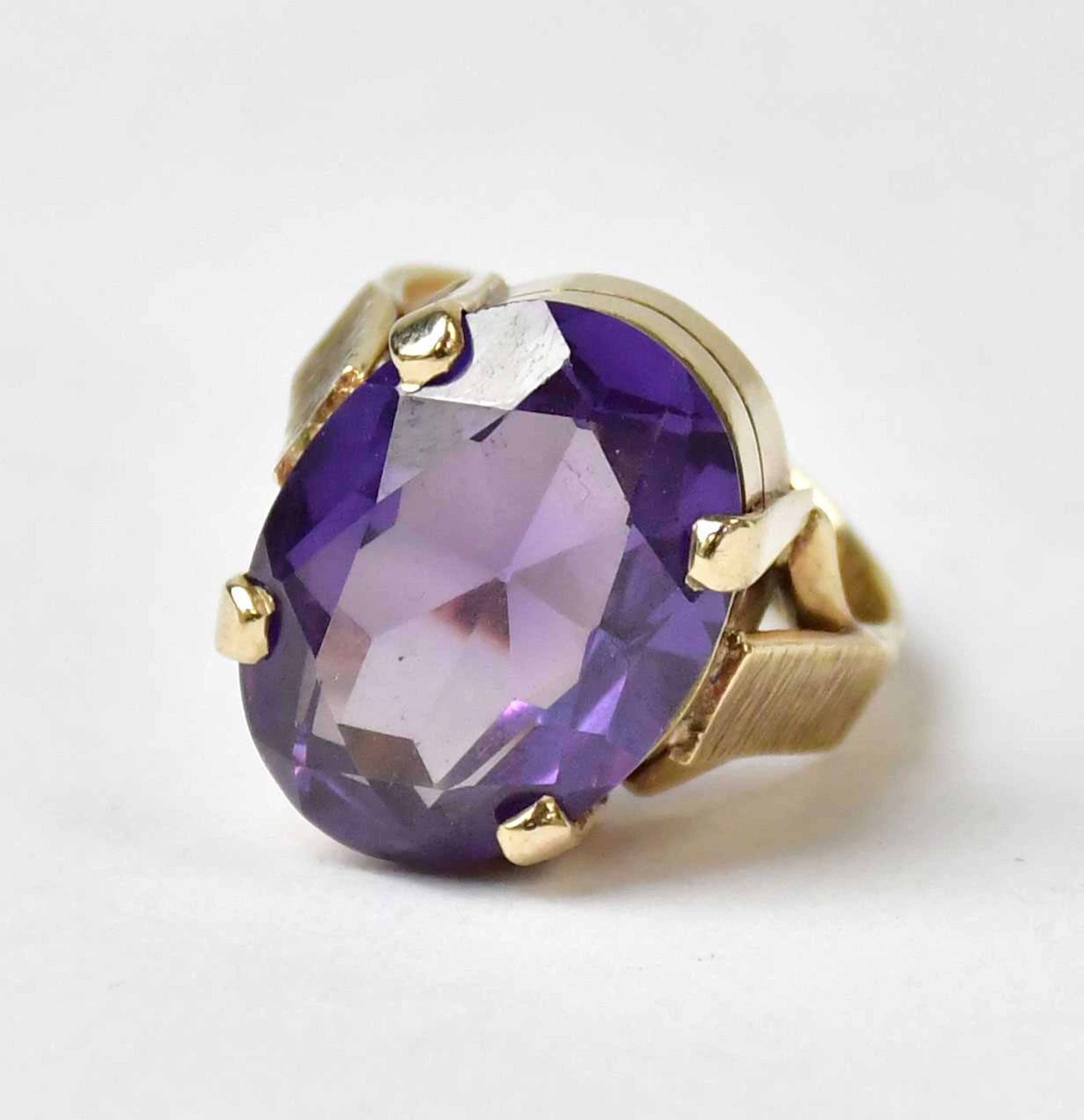 A 9ct yellow gold ring set with an oval purple faceted cabochon