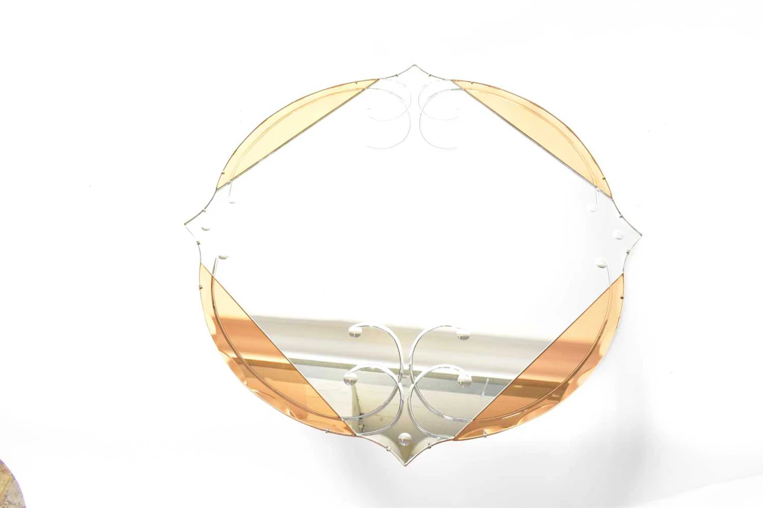 A vintage peach and clear glass mirror with etched scroll decoration