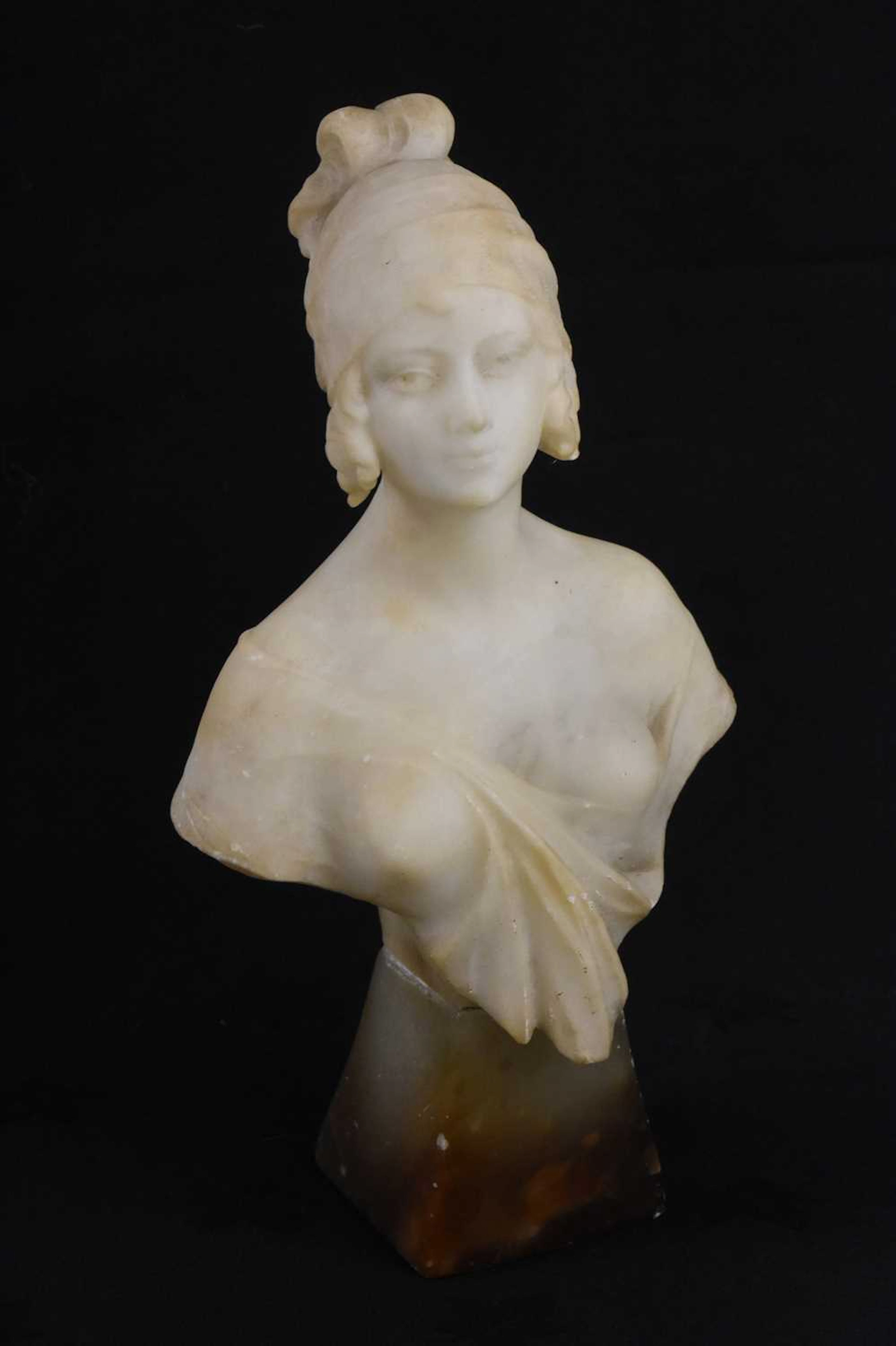An Art Deco carved alabaster bust on tapering stand