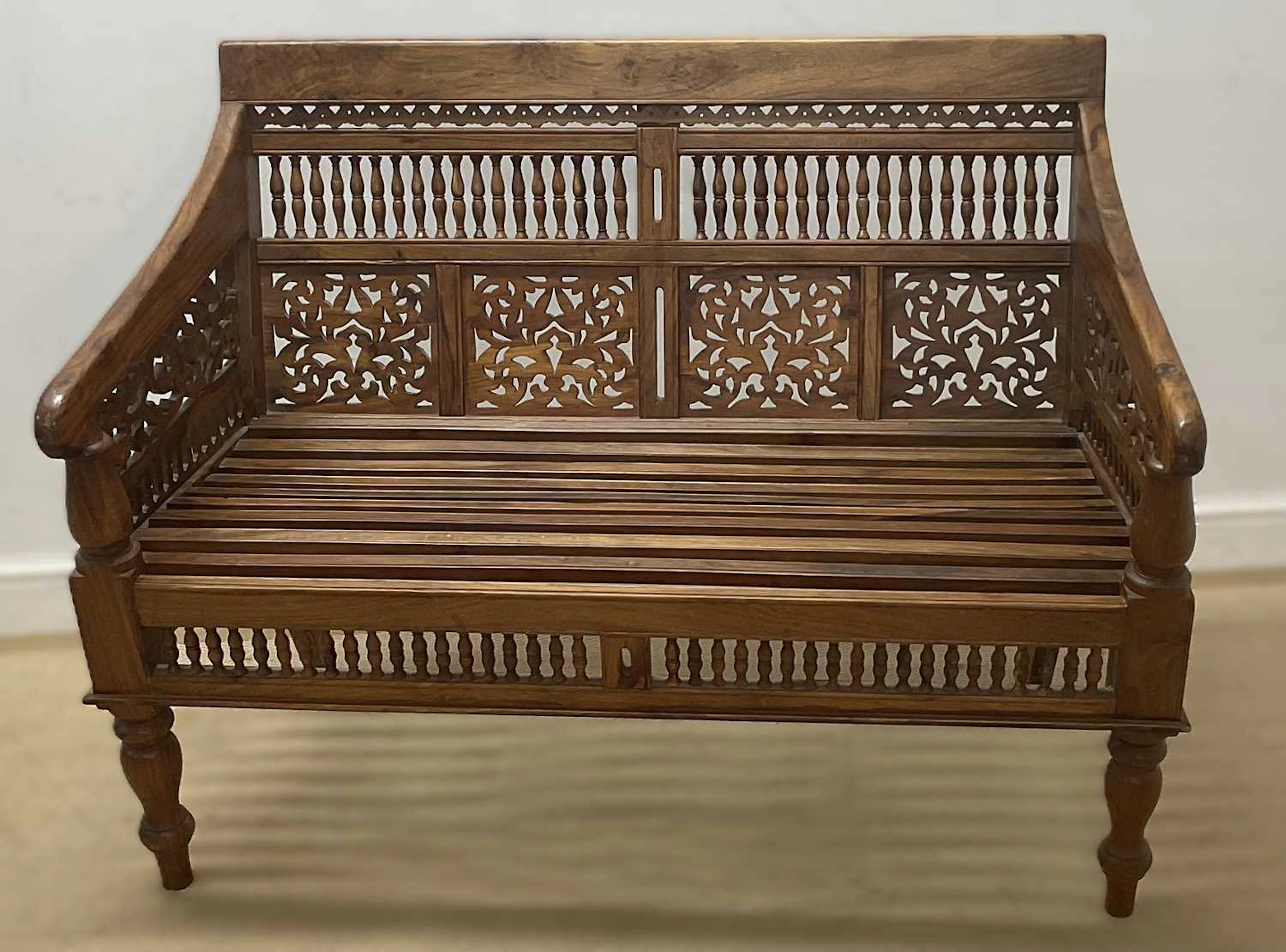 A stained teak two seater bench having a slat seat