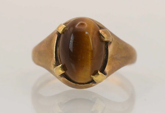 A 9ct rose gold signet ring with four claw set tiger's eye stone
