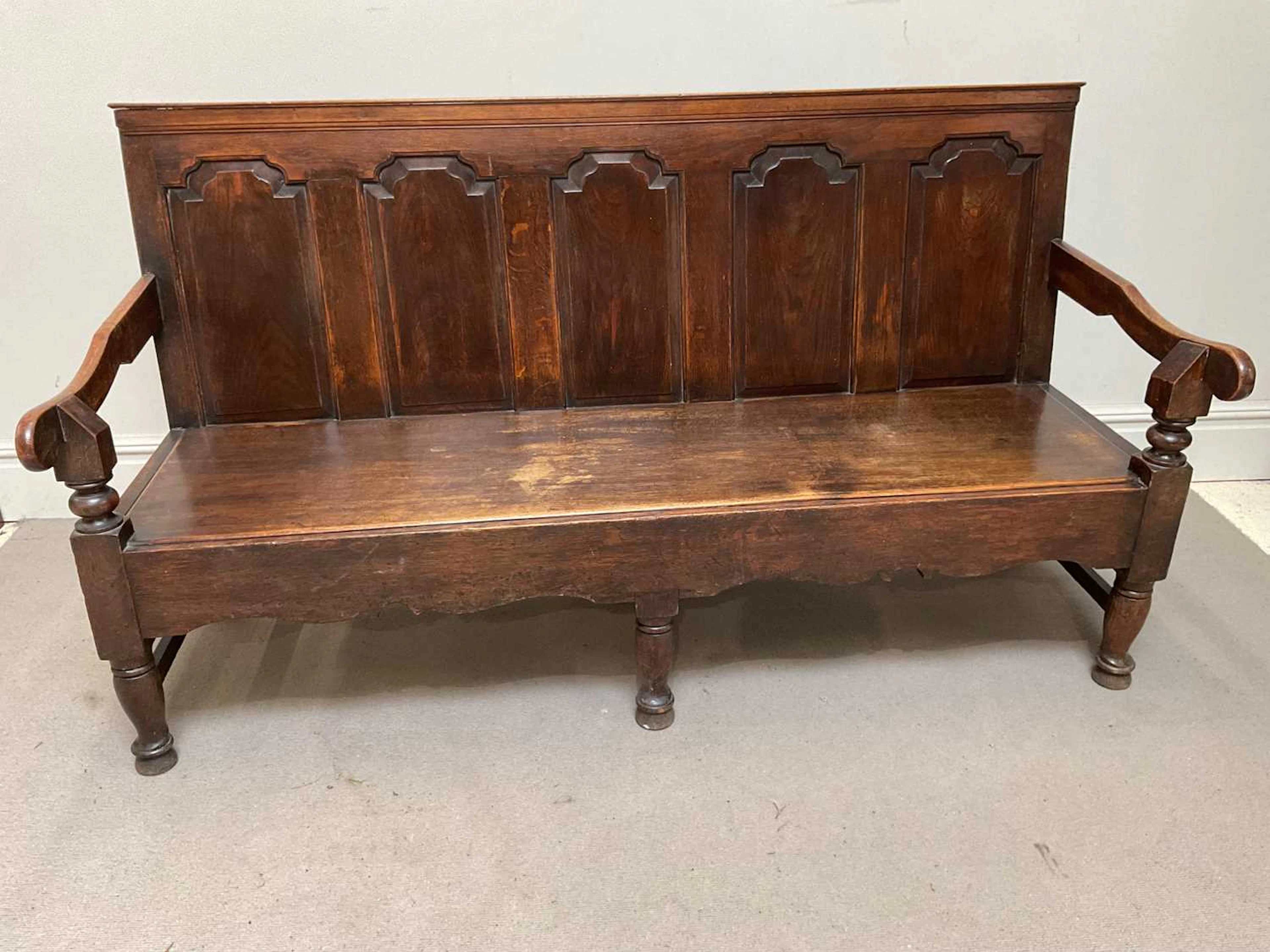 An 18th century carved and panelled oak settle