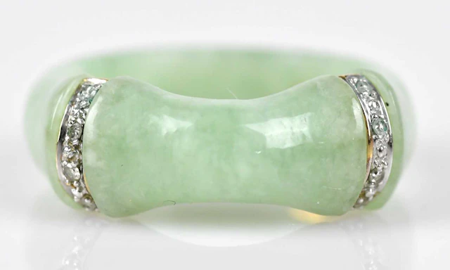 A Chinese green hardstone dress ring set with two yellow and white metal bands