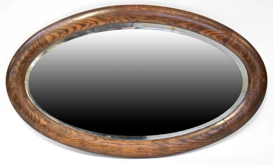 An oak framed oval wall mirror with bevelled plate