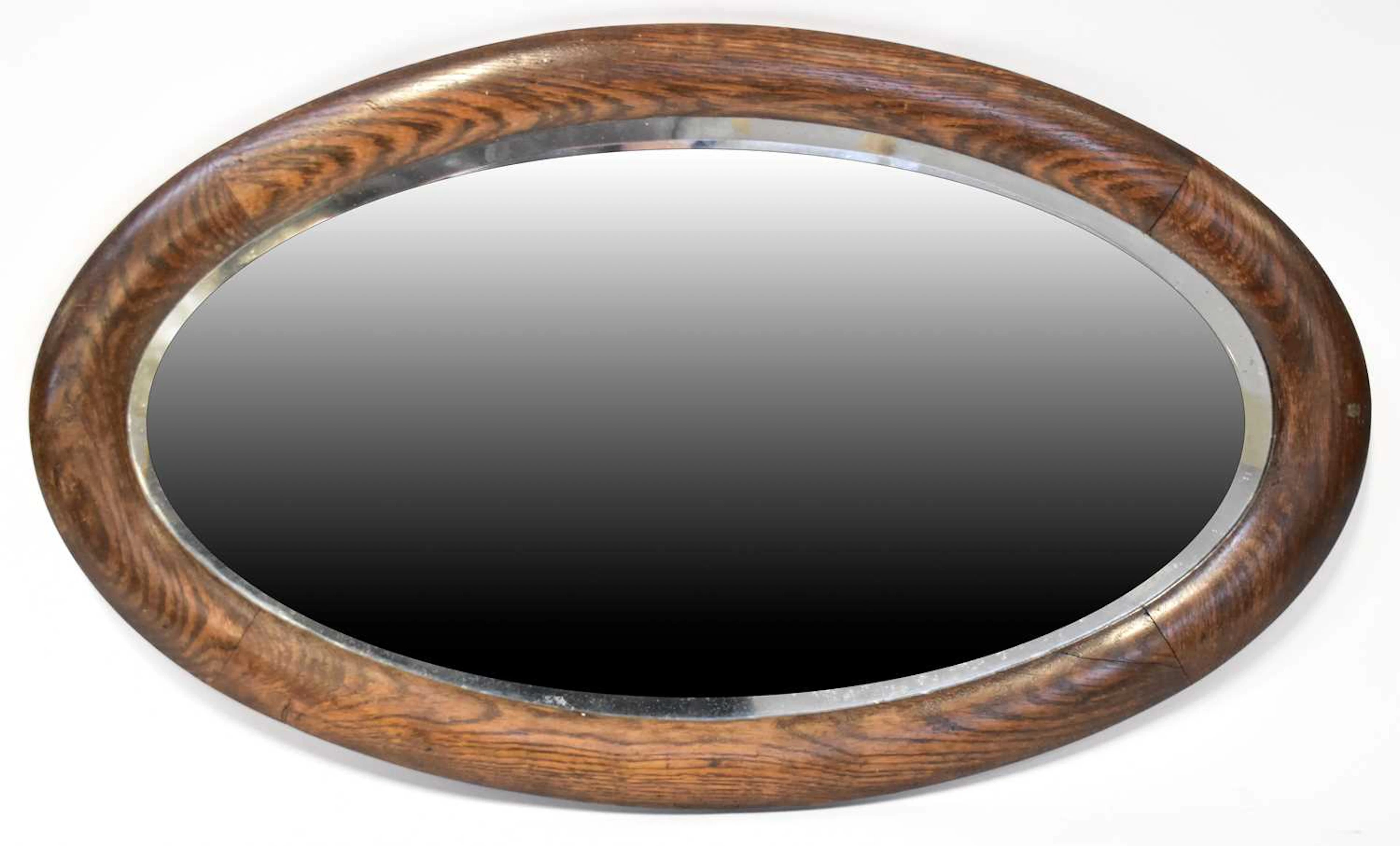 An oak framed oval wall mirror with bevelled plate