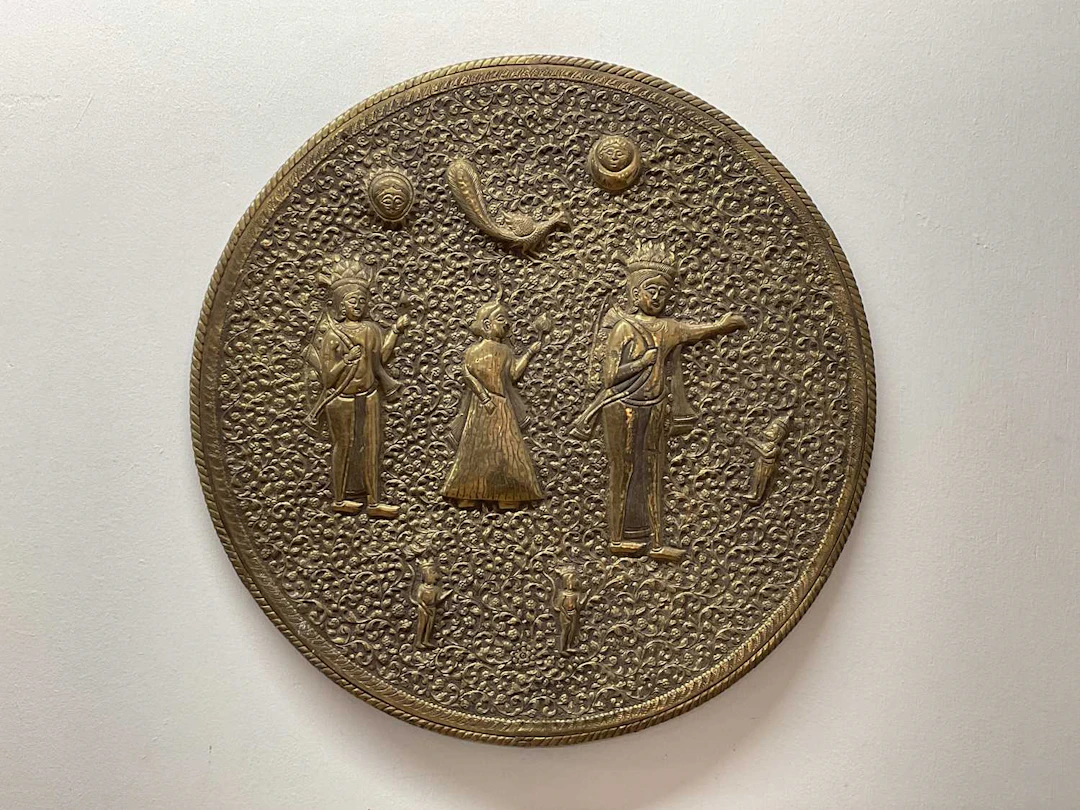 An Indian brass wall charger depicting figures and...