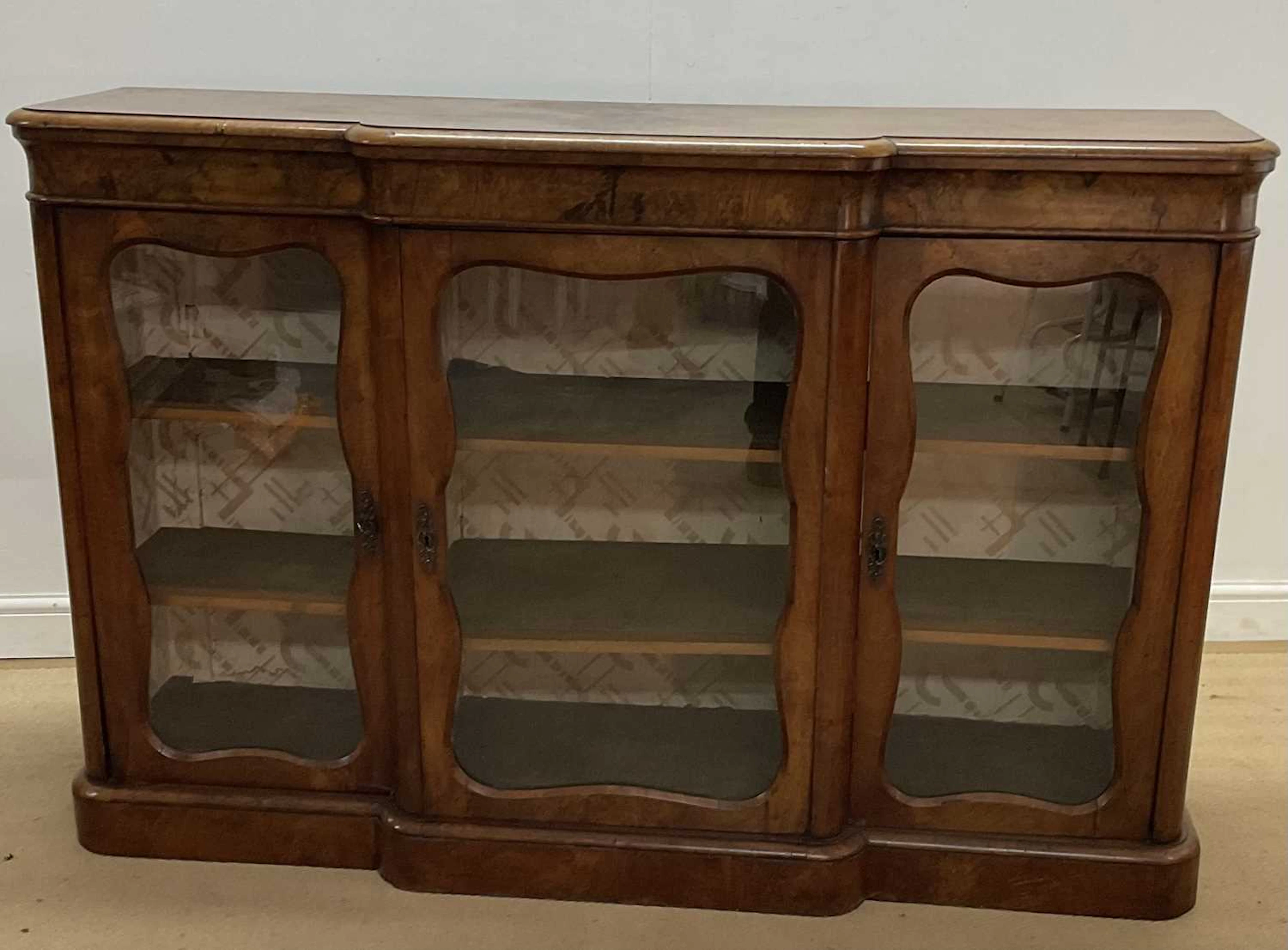 A burr walnut breakfront credenza with a central section...