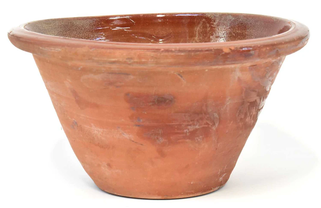 A large brown glazed earthenware rustic mixing bowl