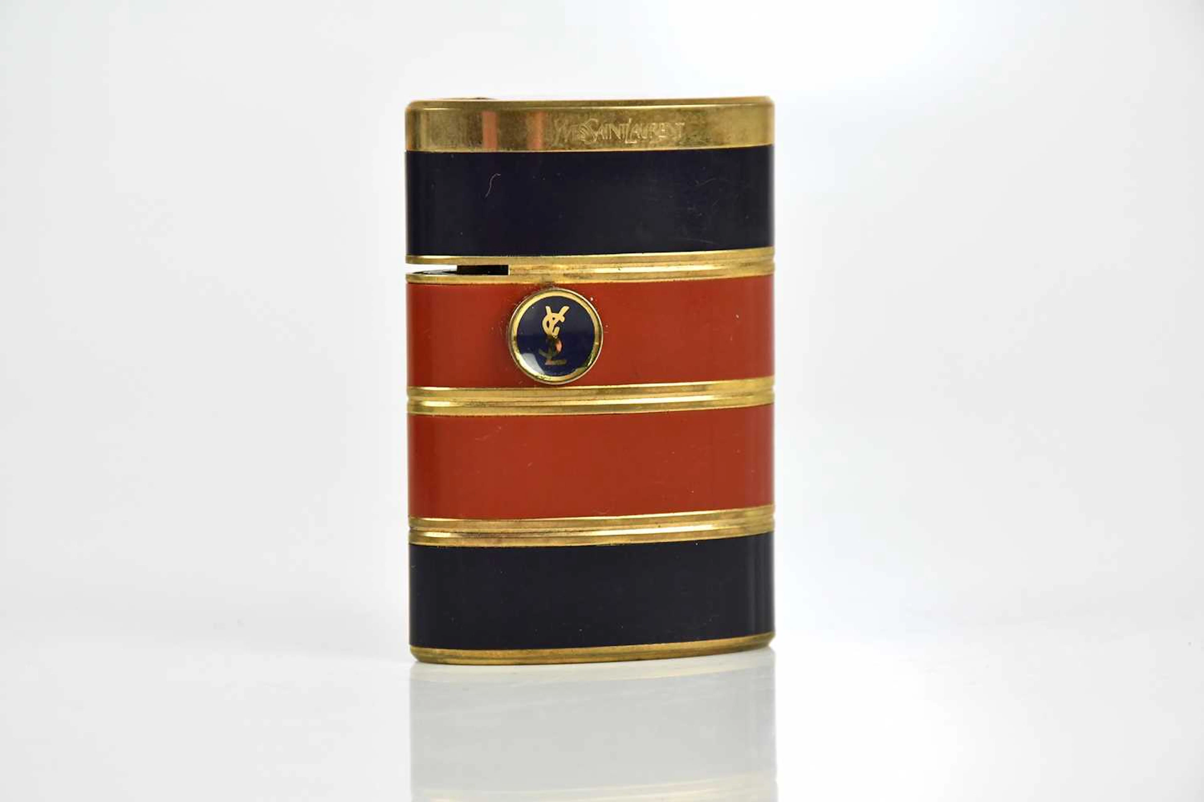 YVES SAINT LAURENT; a gold tone and black and tan lacquered lighter