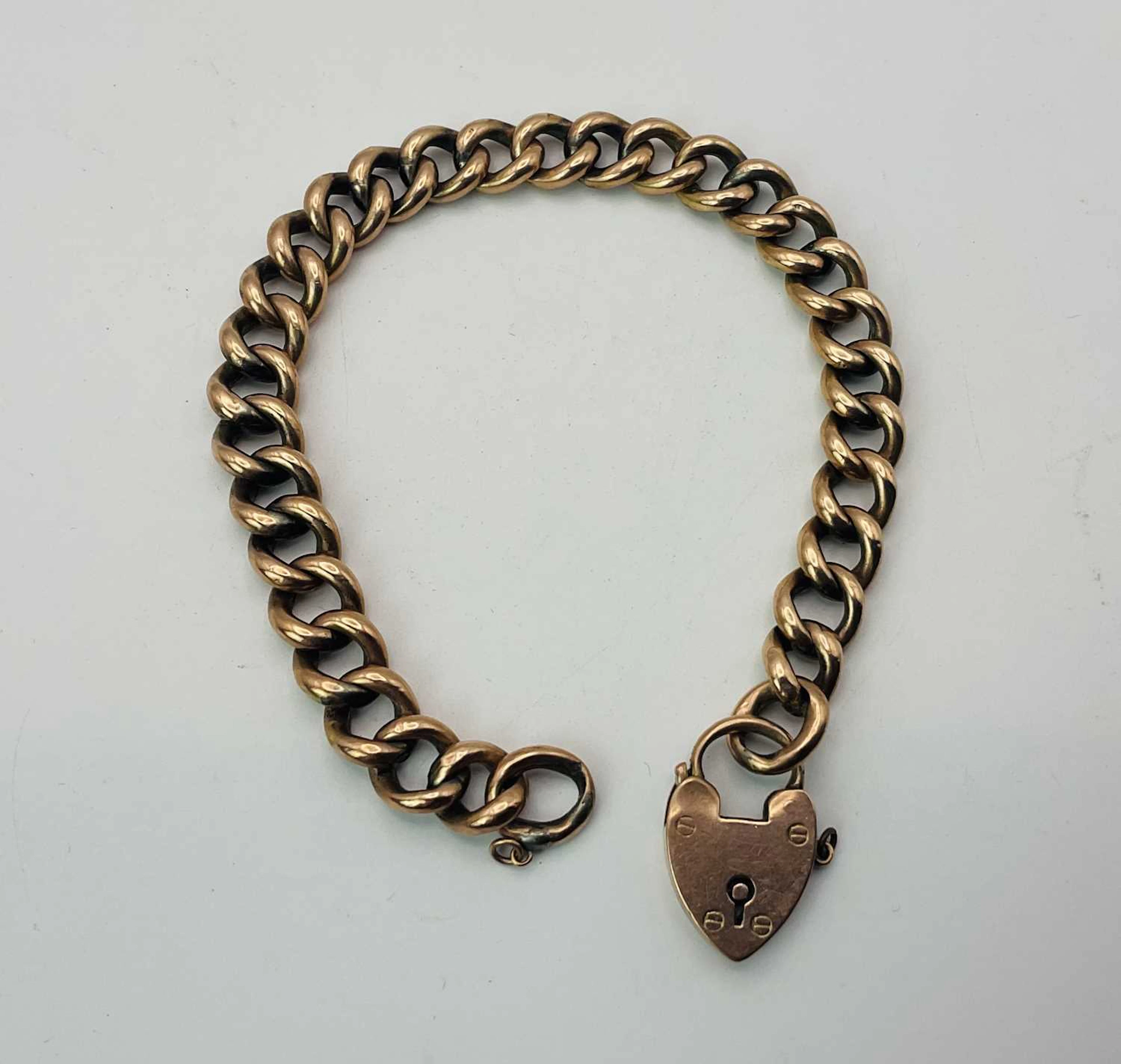 A 9ct rose gold Edwardian curb link bracelet with heart locket clasp
