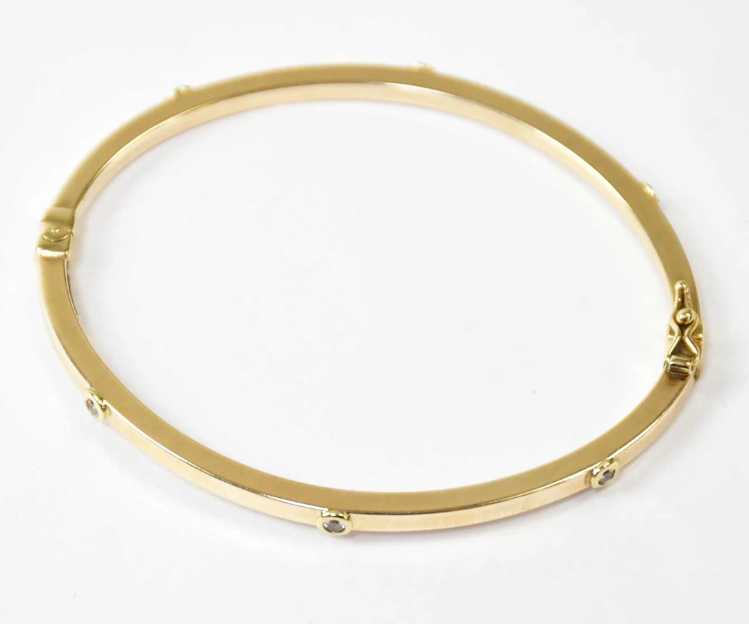 A 9ct yellow gold hinged bangle set with six white stones