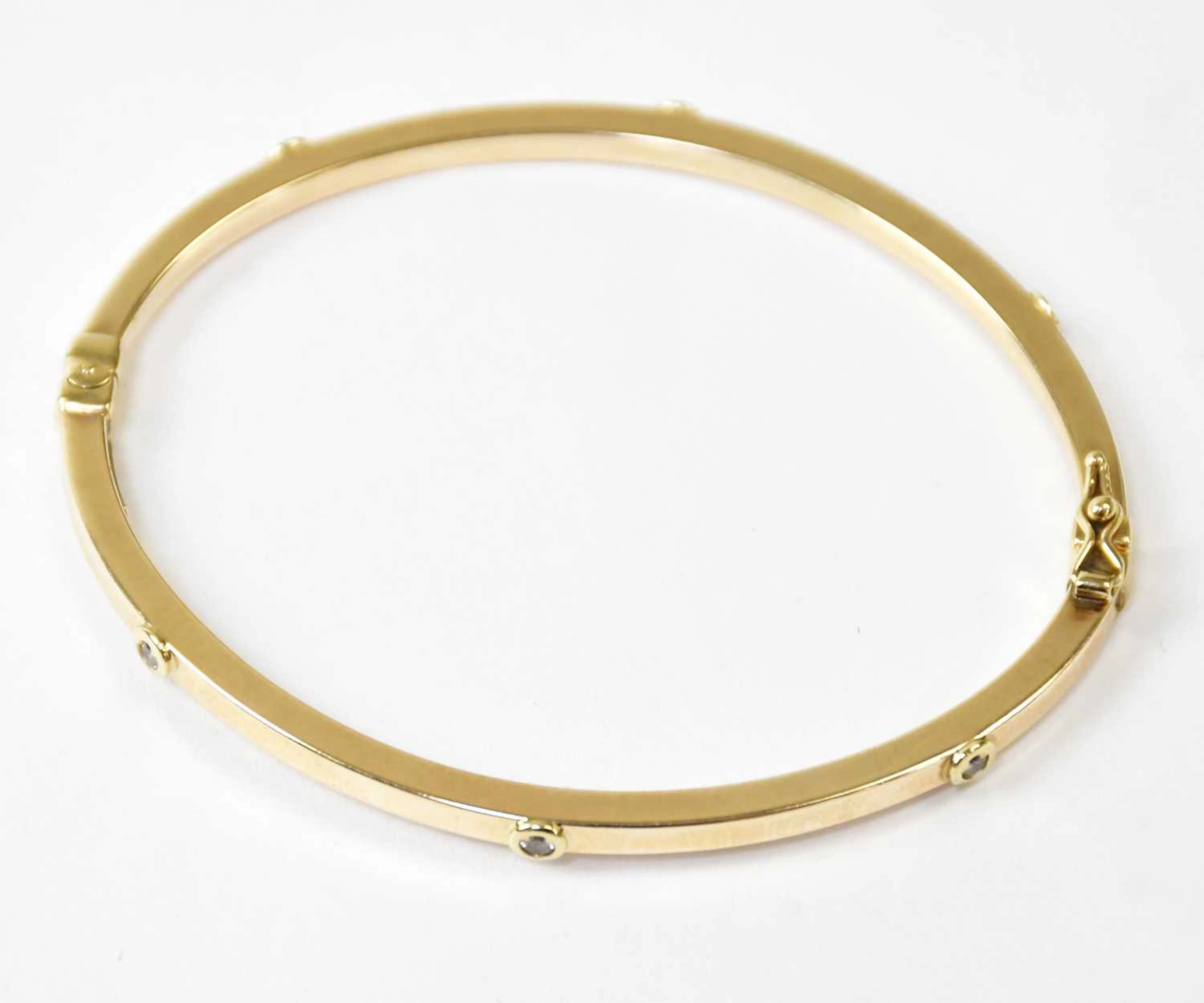 A 9ct yellow gold hinged bangle set with six white stones