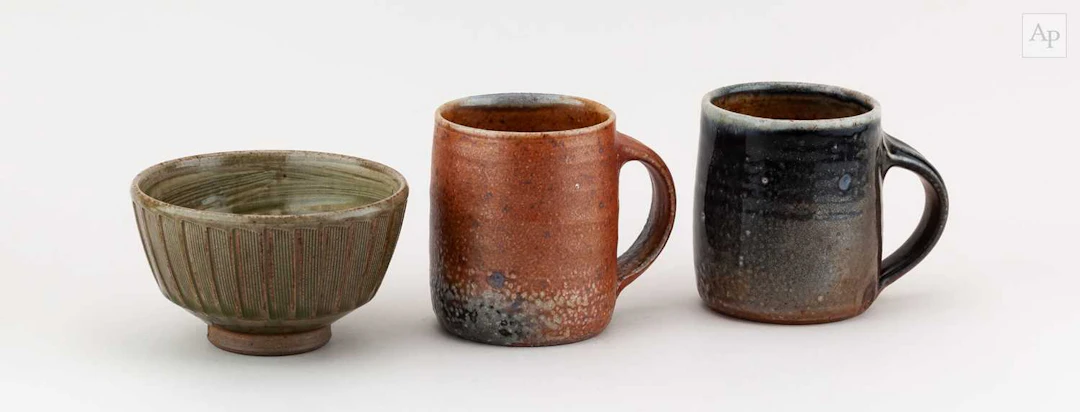 Maze Hill Pottery; a near pair of stoneware mugs covered in soda shino glaze