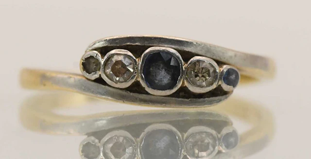 An 18ct yellow gold five stone sapphire and diamond set crossover dress ring