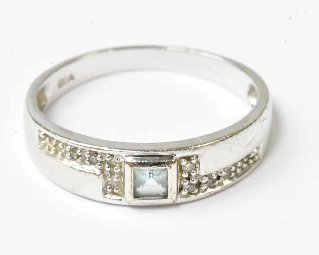 A 9ct white gold ring set with a central princess cut...