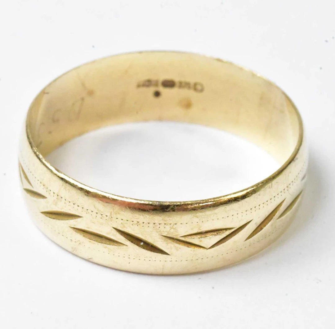 A 9ct yellow gold wedding band with engraved decoration