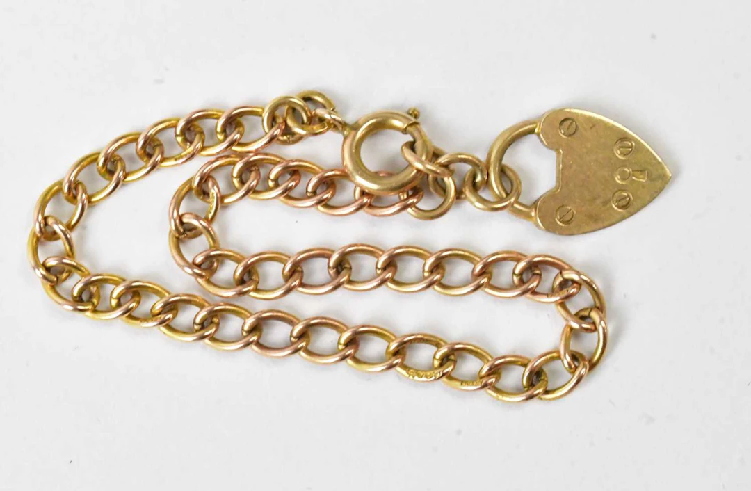 A 9ct yellow gold curb link bracelet with a 9ct gold heart shapred padlock clasp