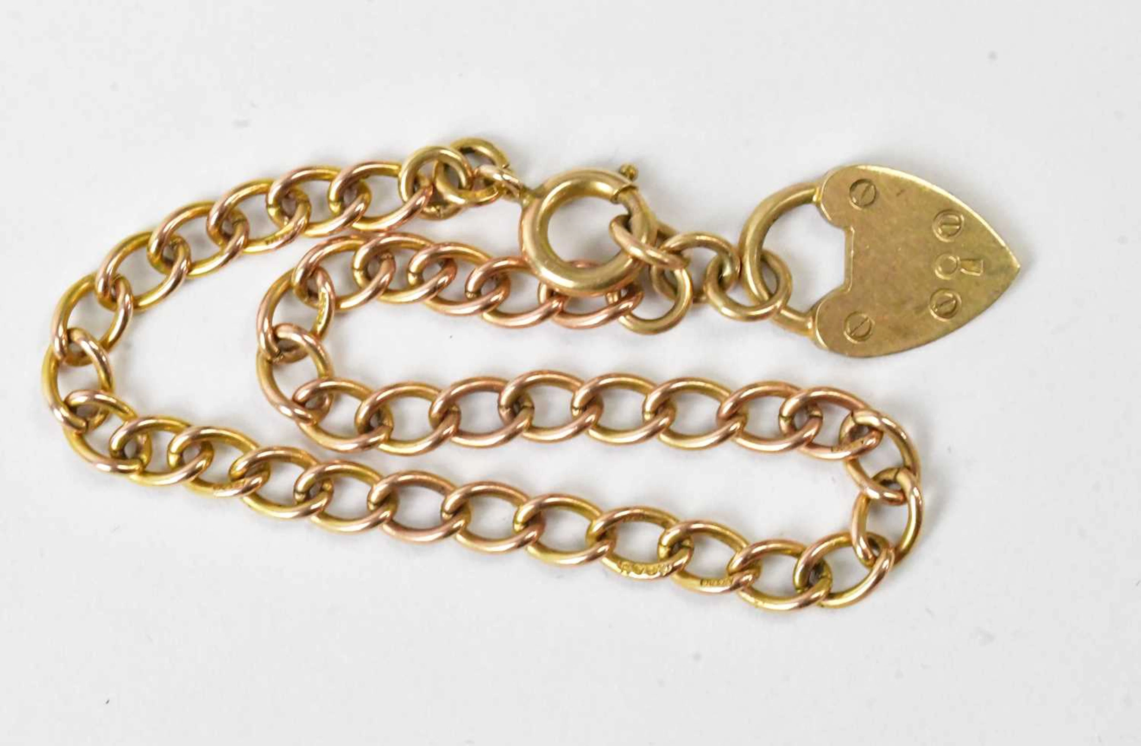 A 9ct yellow gold curb link bracelet with a 9ct gold heart shapred padlock clasp
