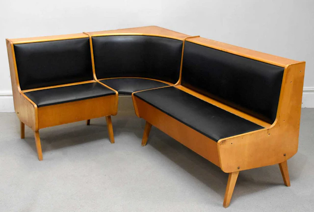 A retro teak corner lounge suite upholstered in a black vinyl material