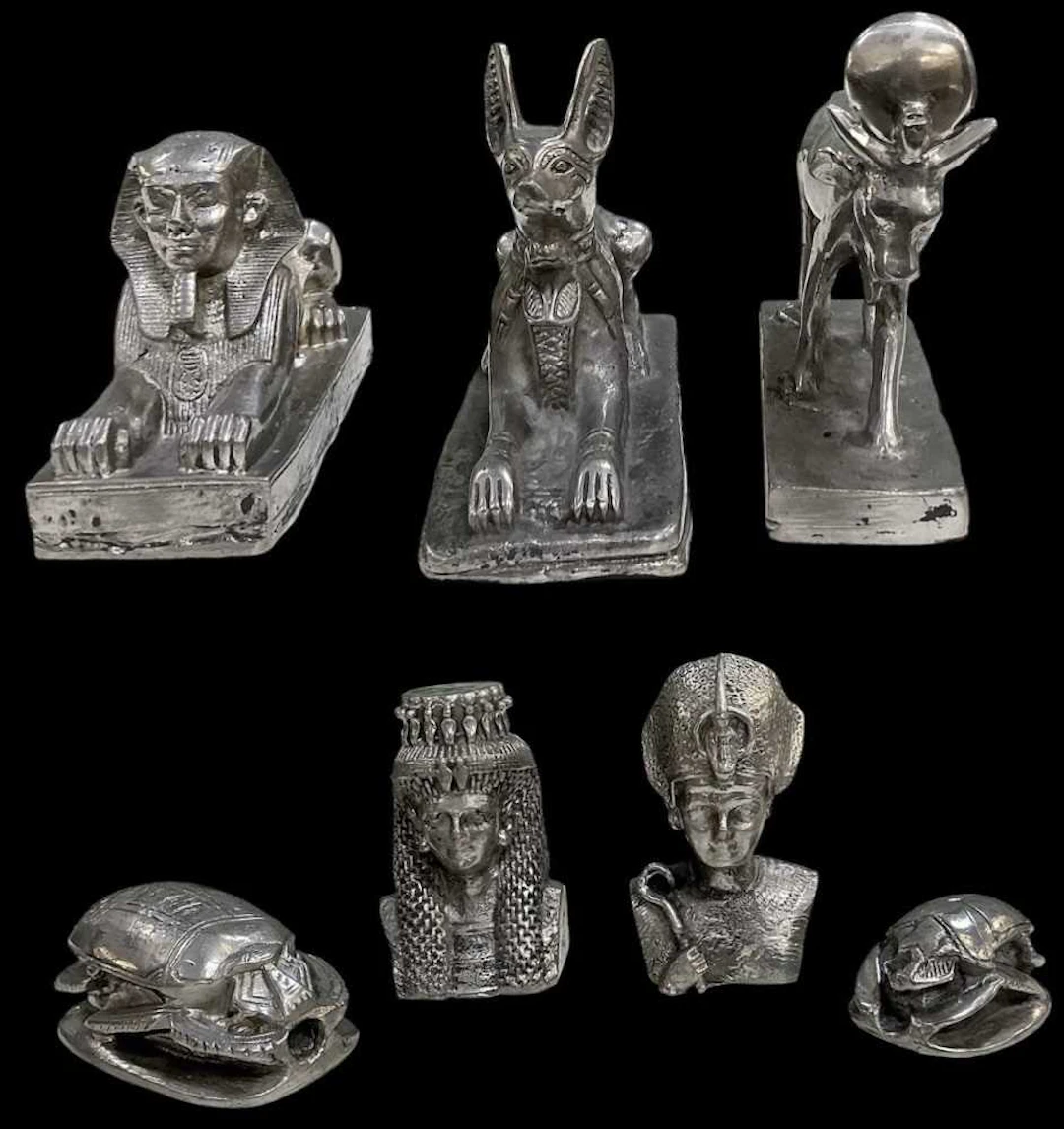Seven assorted Egyptian Revival pewter figures including two recumbent sphinxes