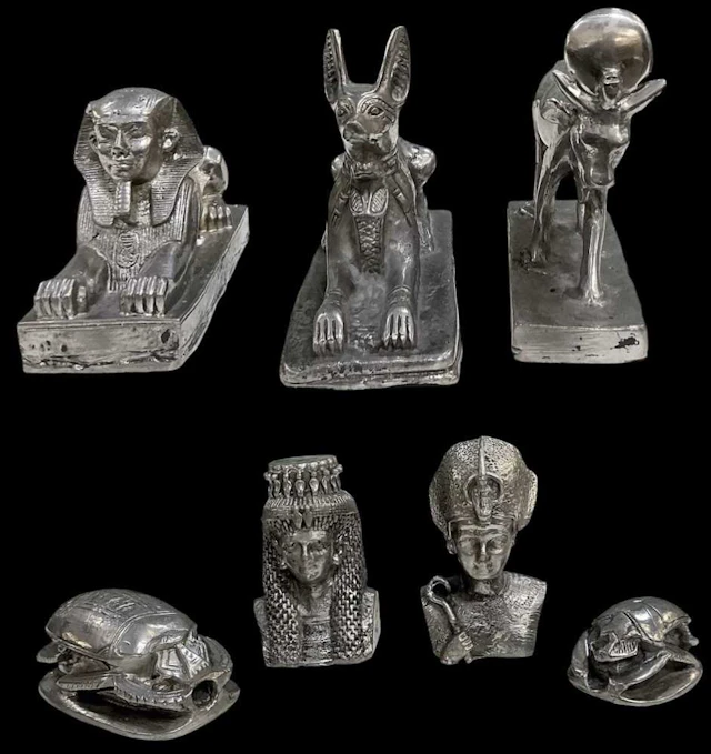 Seven assorted Egyptian Revival pewter figures including two recumbent sphinxes