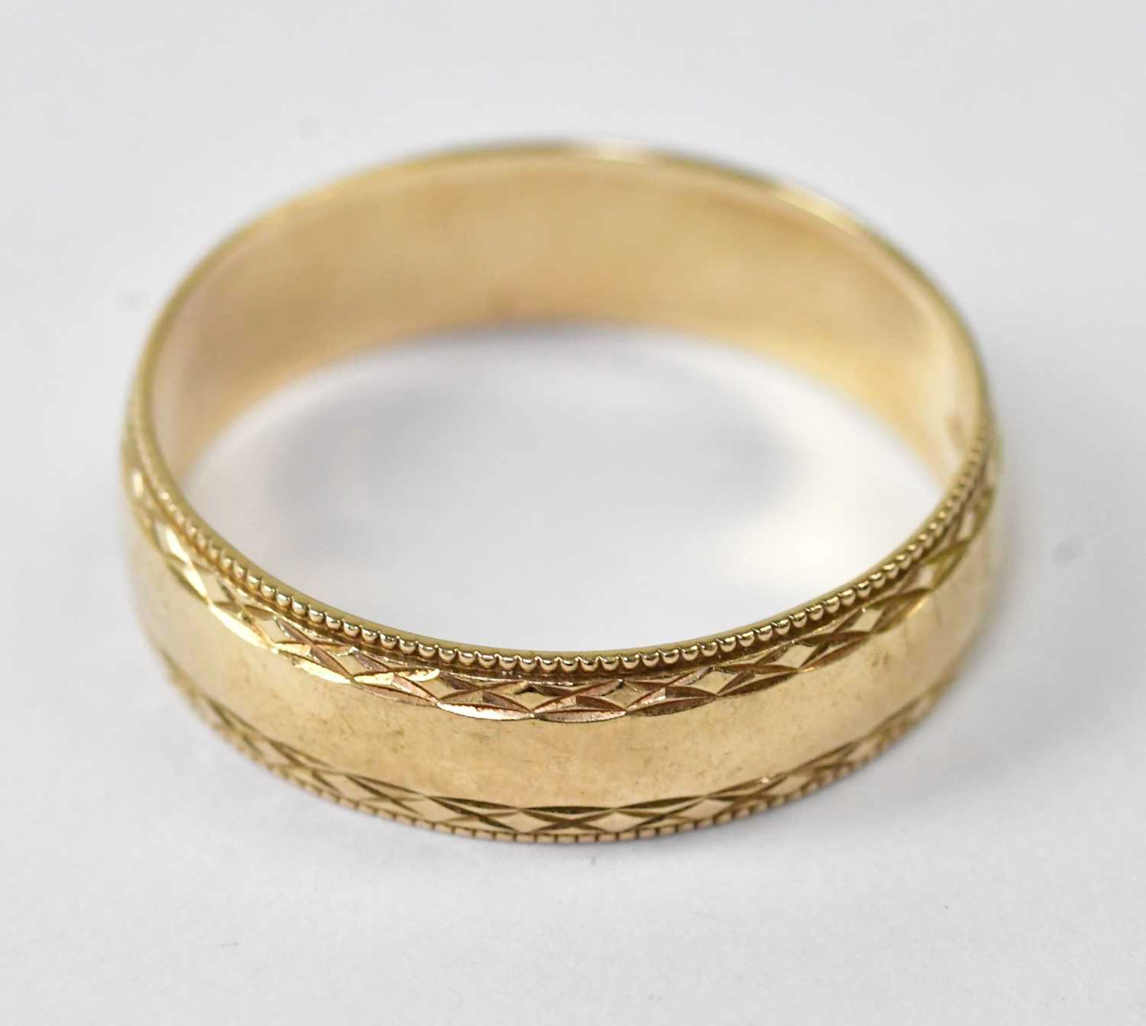 A 9ct yellow gold wedding band with engraved and beaded decoration