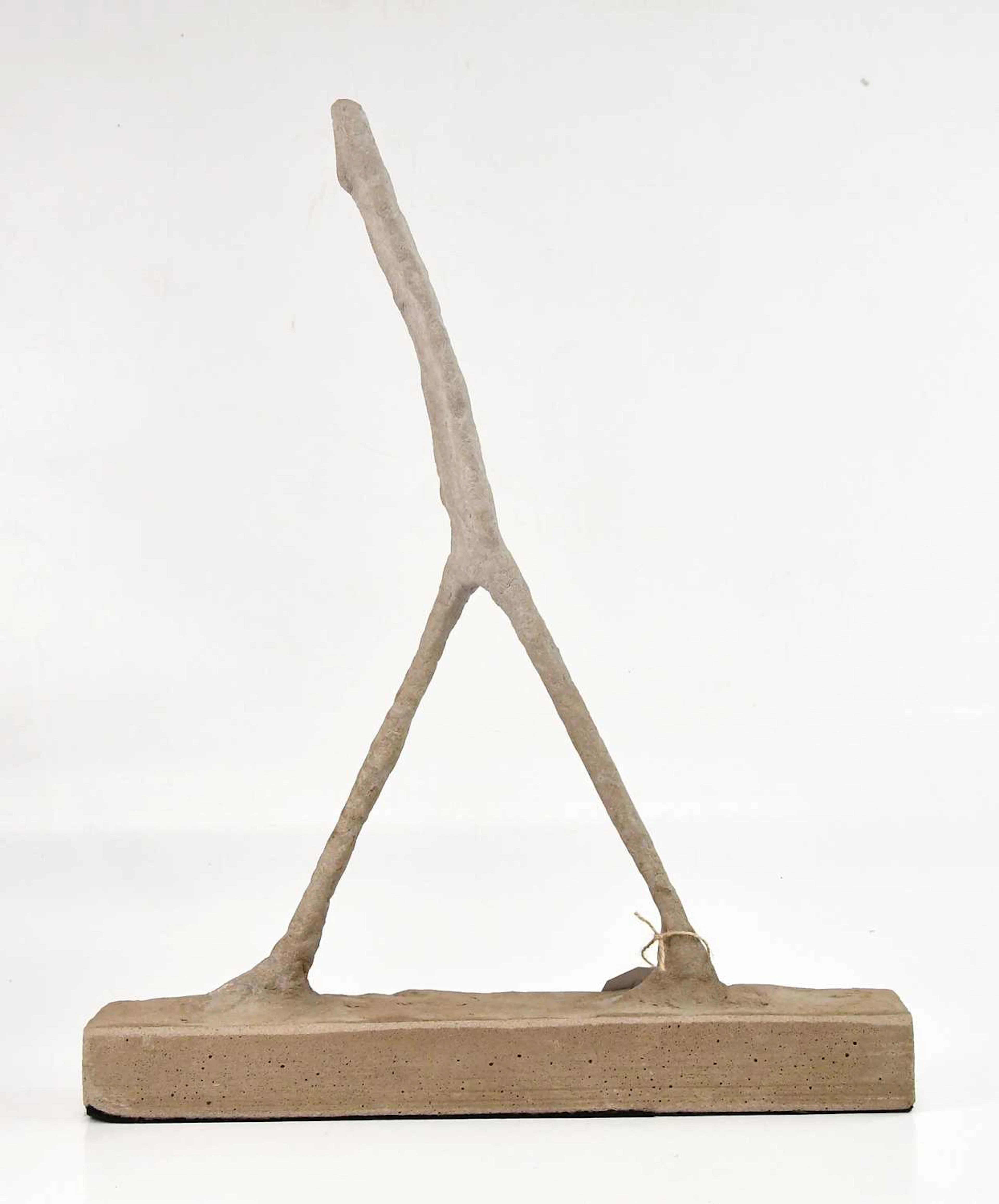 An Alberto Giacometti style concrete sculpture of a walking figure